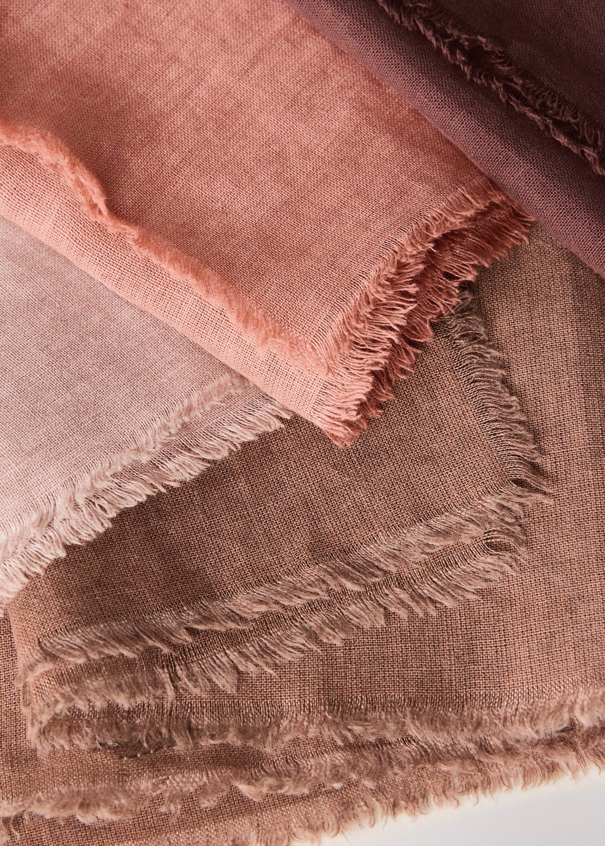 Close-up of textured fabric napkins with frayed edges in muted earth tones.