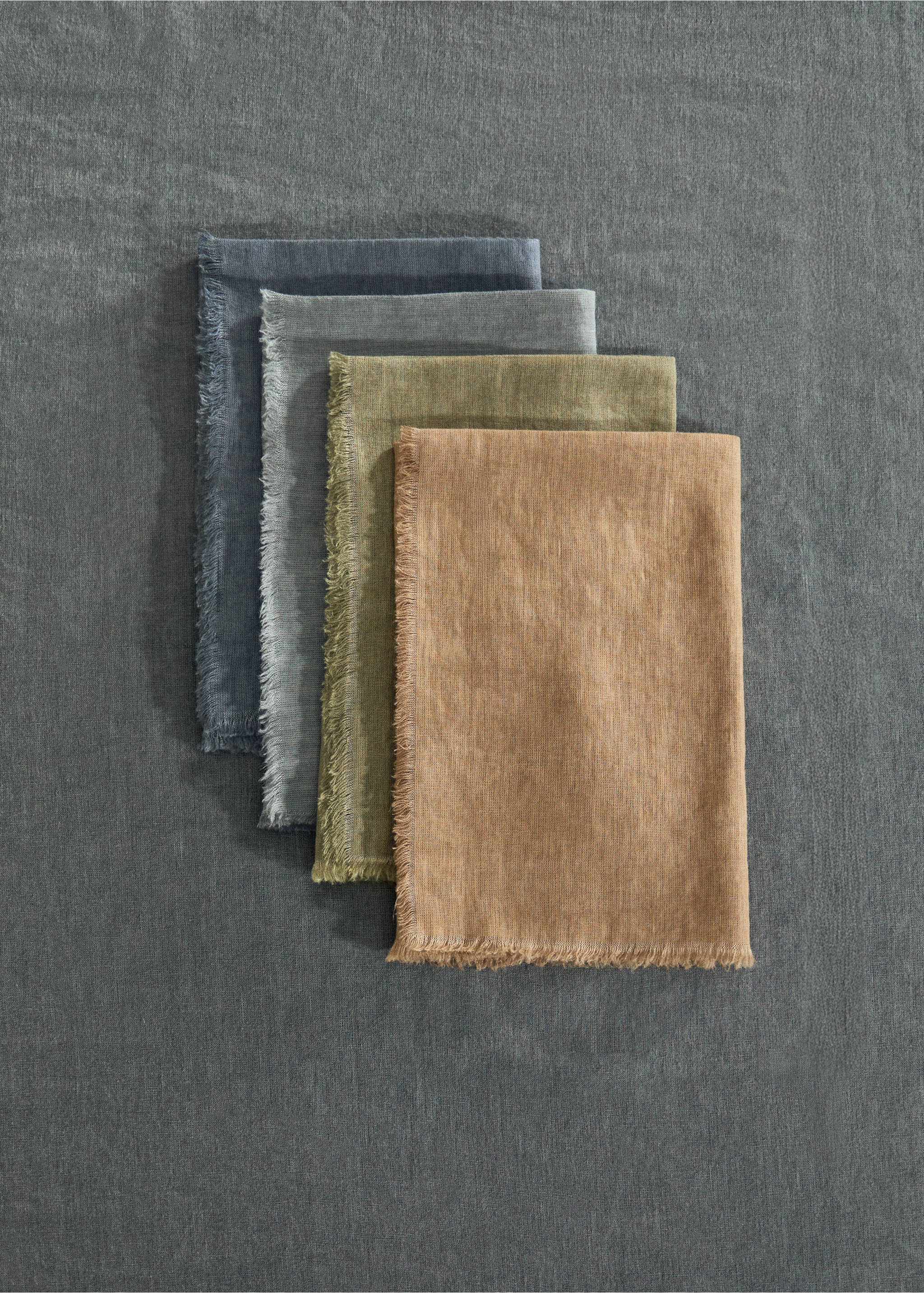 Four folded fringed napkins stacked in blue, grey, olive, and ochre., Ink Blue. Ref: 17083321-00.