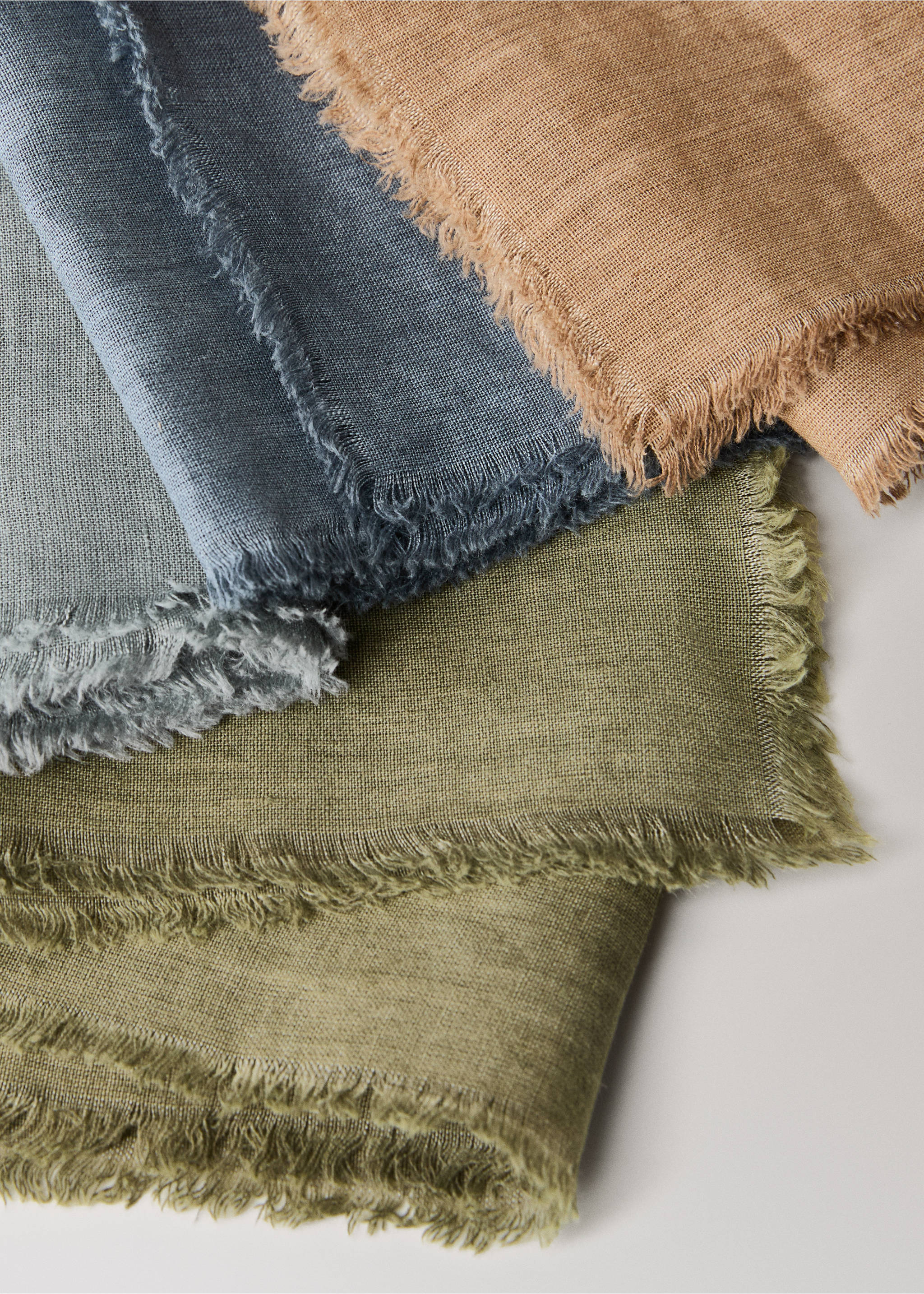 Close-up of fringed fabric napkins in camel, grey-blue, and olive green., Ink Blue. Ref: 17083321-00.