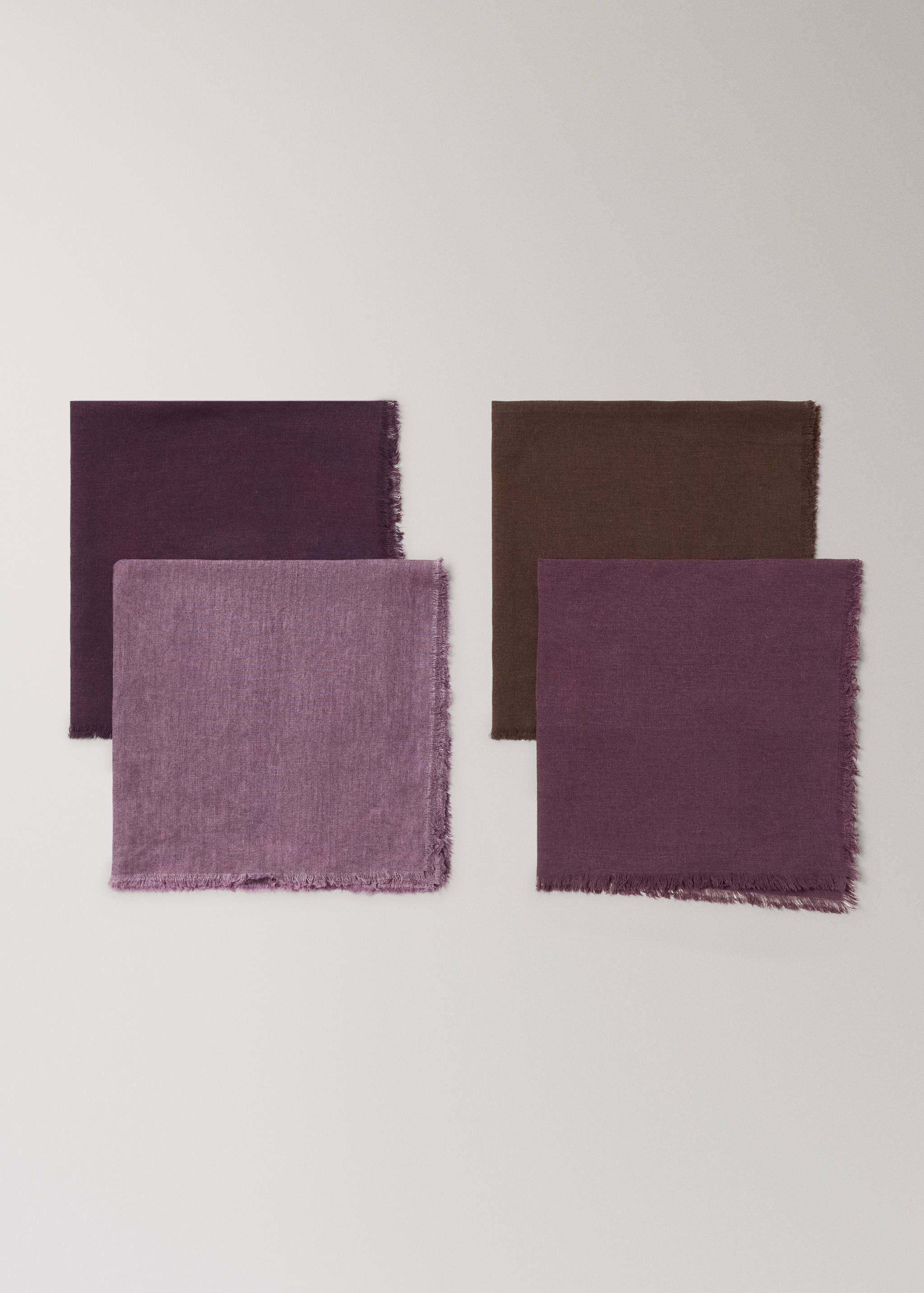 Set of four square fabric napkins with fringed edges in purple, lilac and brown.