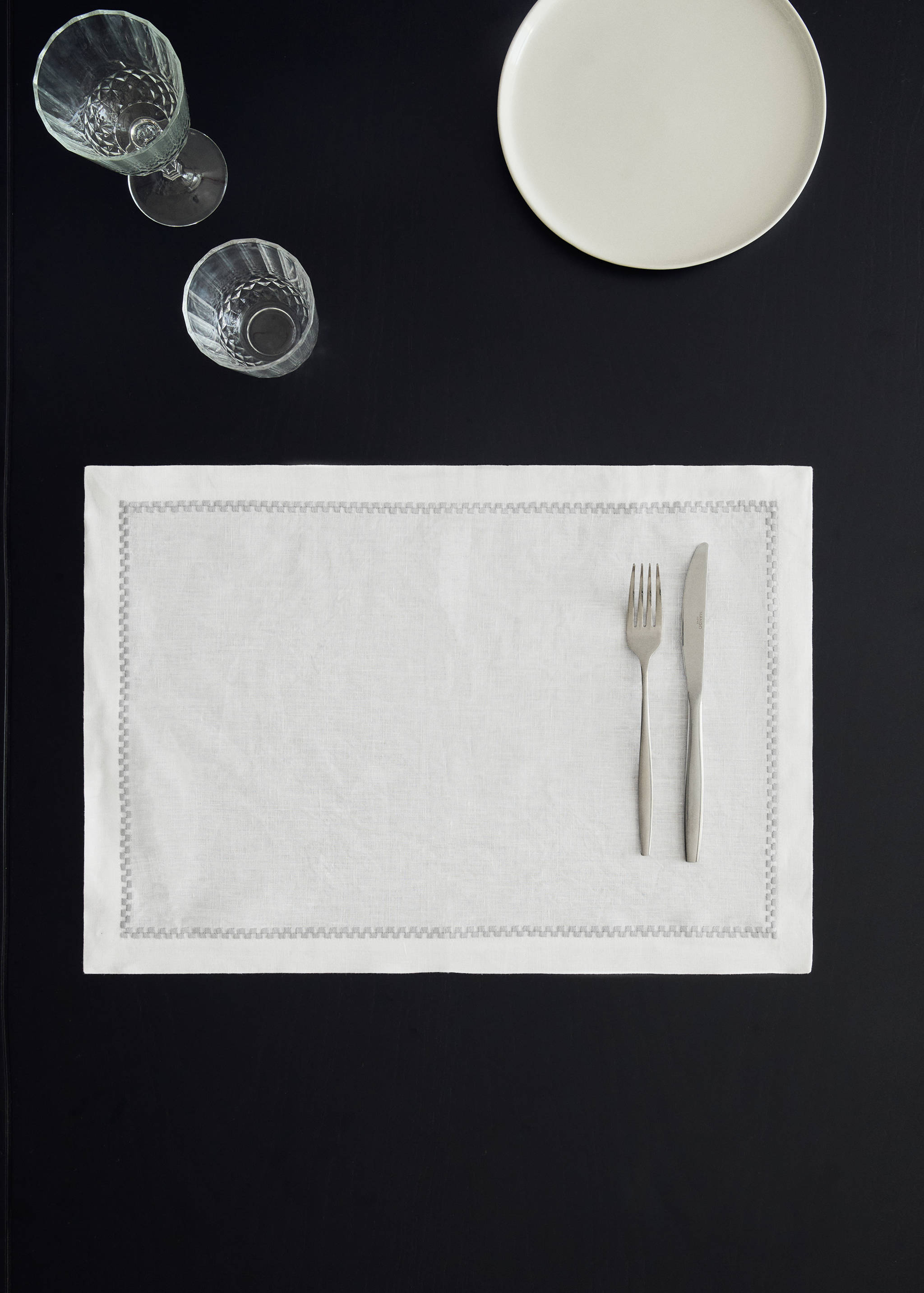 White rectangular placemat with a decorative embroidered border.