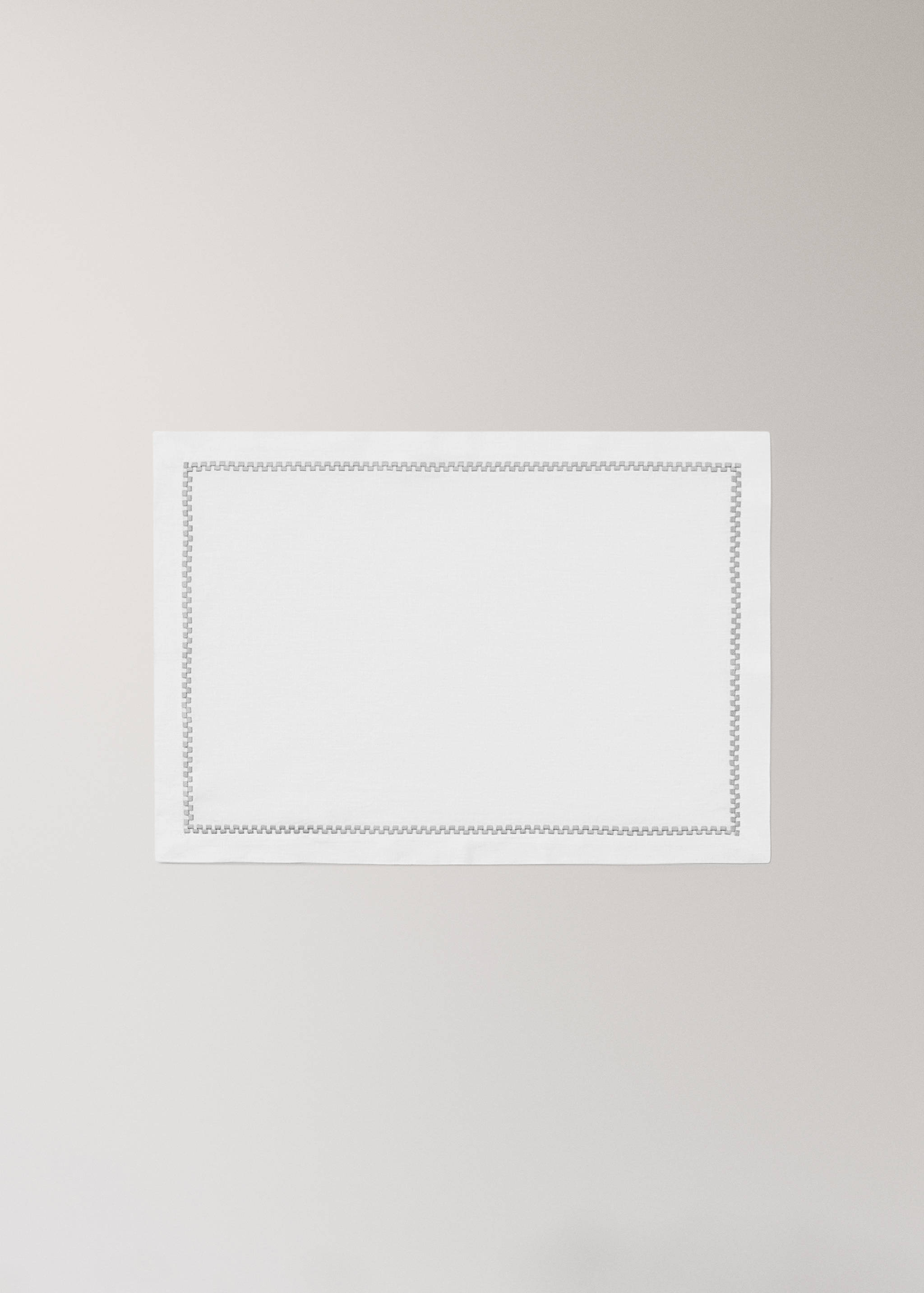 White rectangular placemat with a delicate embroidered geometric border.