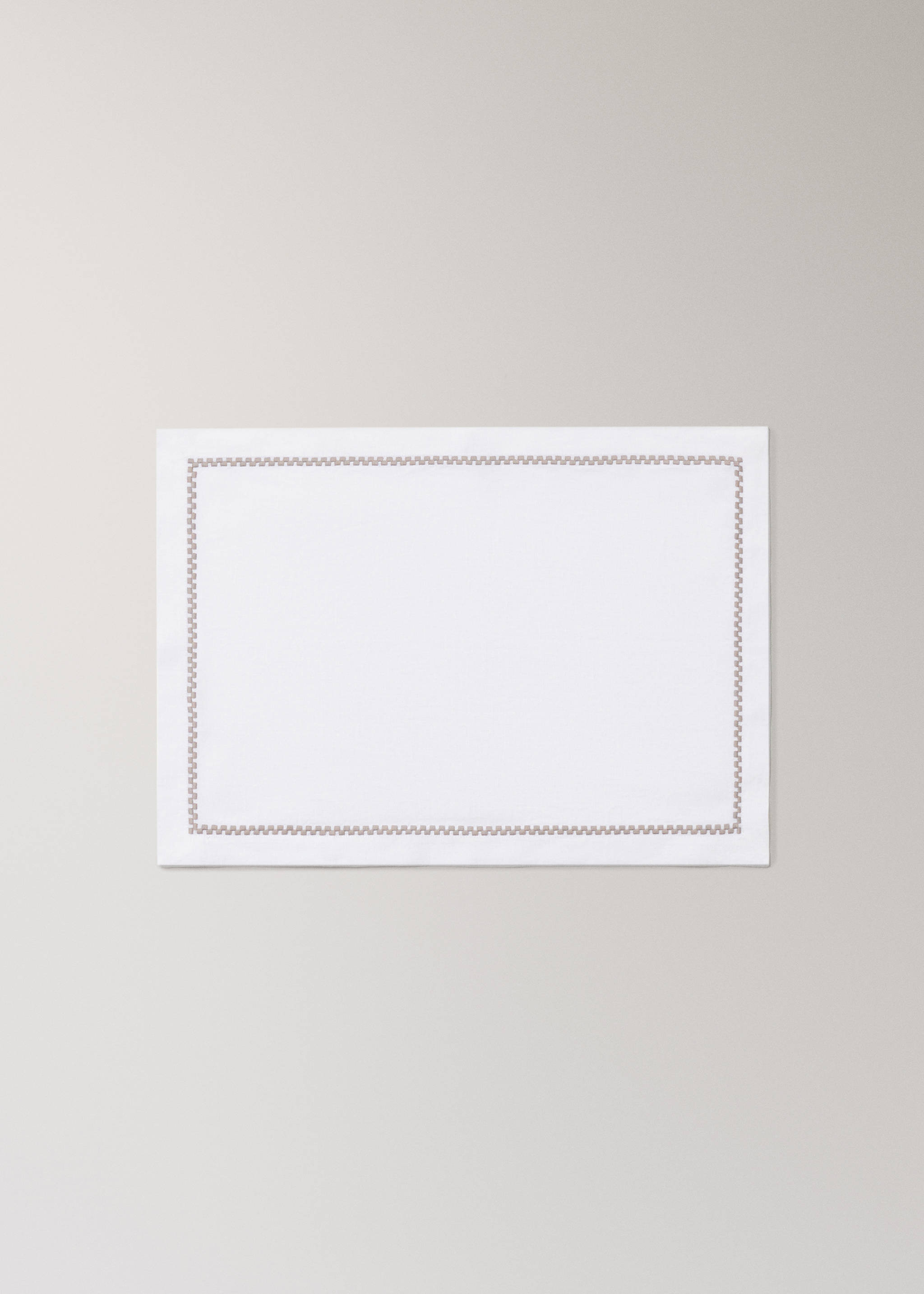 White placemat with a contrasting brown embroidered border.