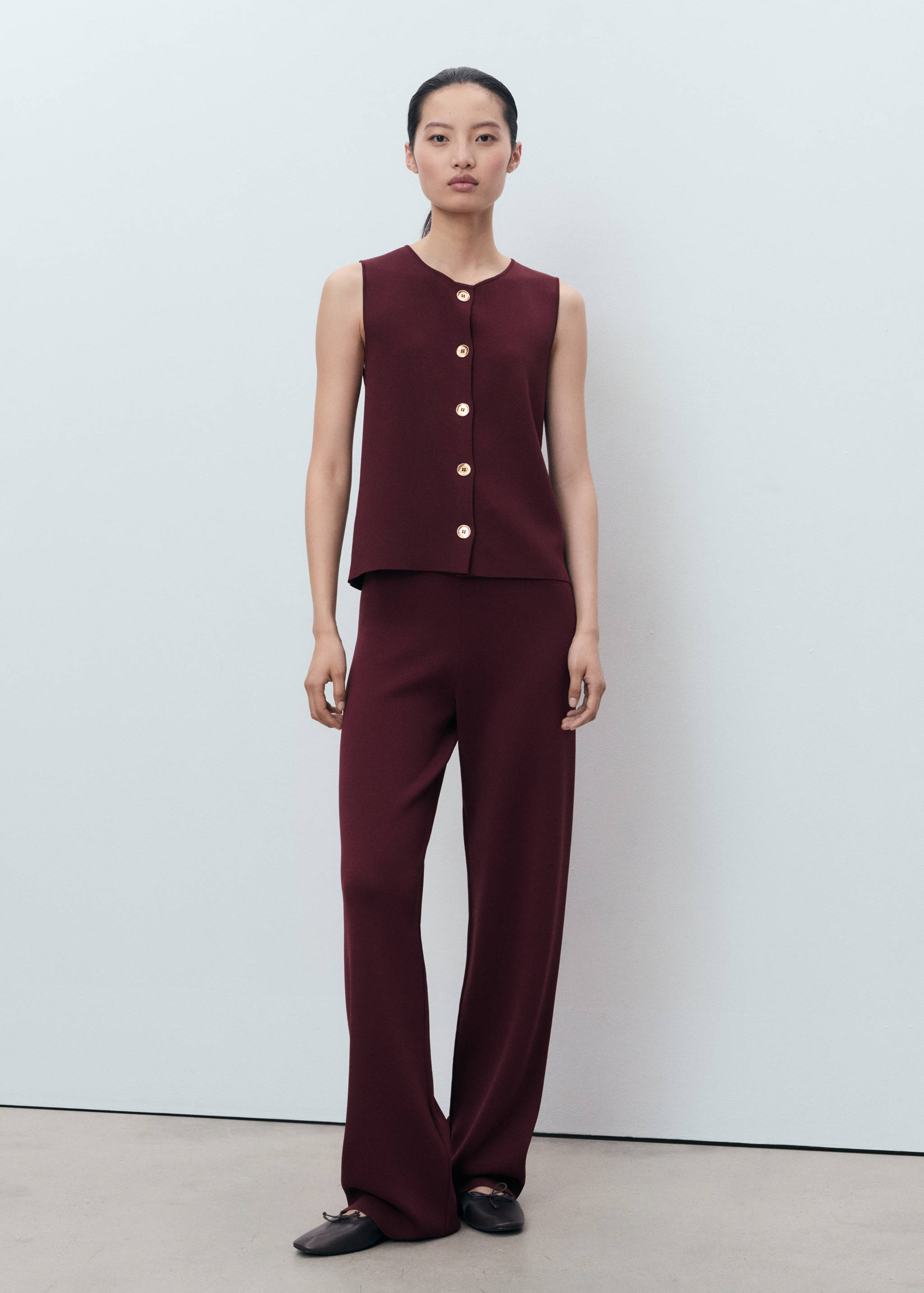 Pantalones burdeos de corte recto, combinados con un top abotonado a juego.