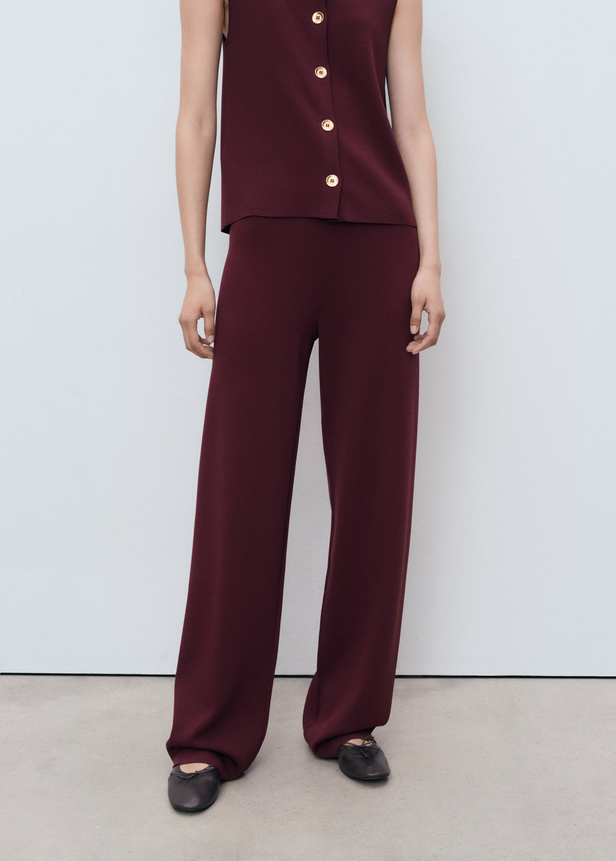 Pantalones largos y rectos de color burdeos combinados con un top sin mangas a juego.