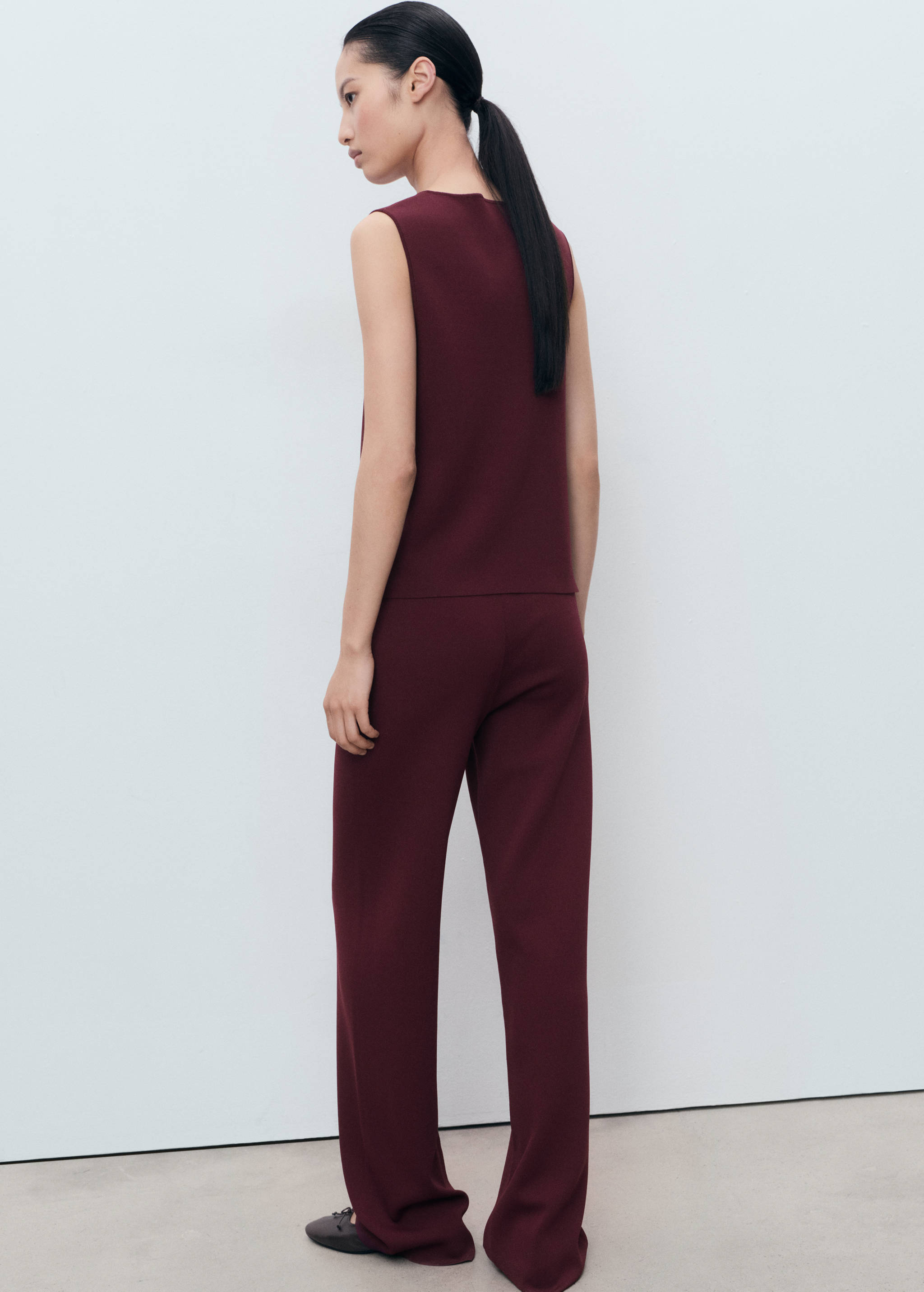 Pantalones burdeos vistos desde atrás con un top sin mangas a juego.
