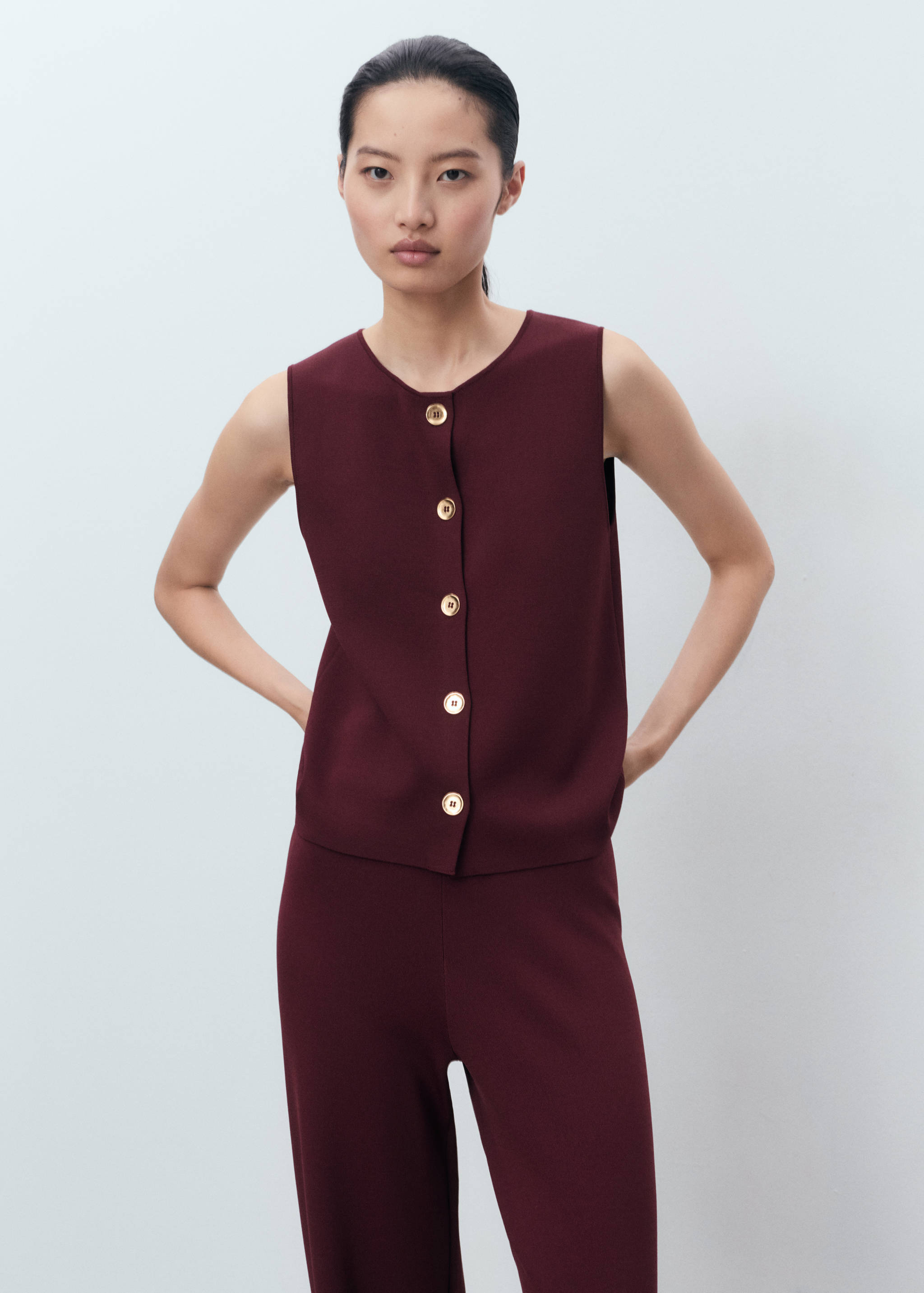 Pantalones burdeos con top sin mangas abotonado a juego.