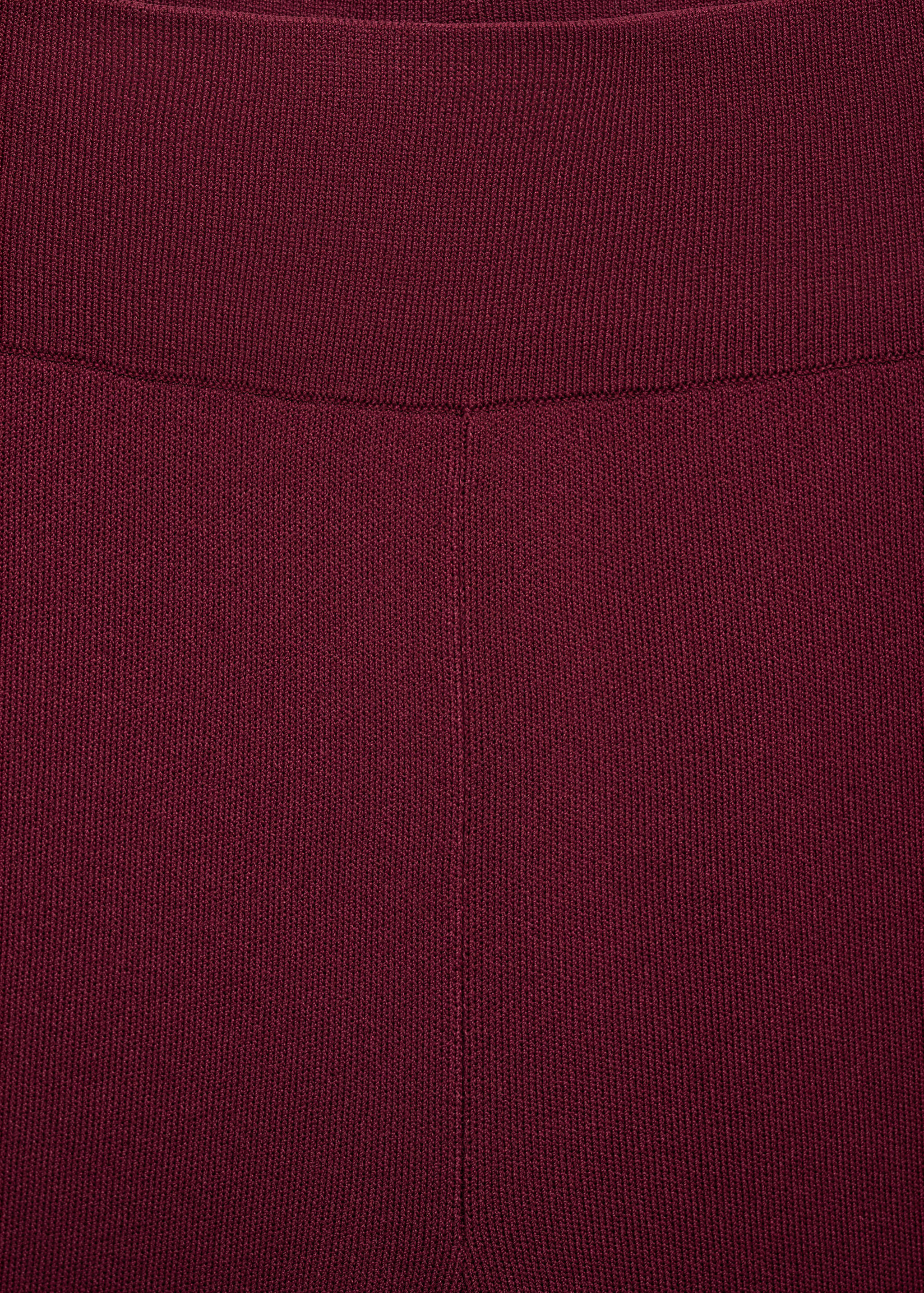 Detalle de los pantalones de punto burdeos que muestra la cintura elástica de canalé y el tejido.