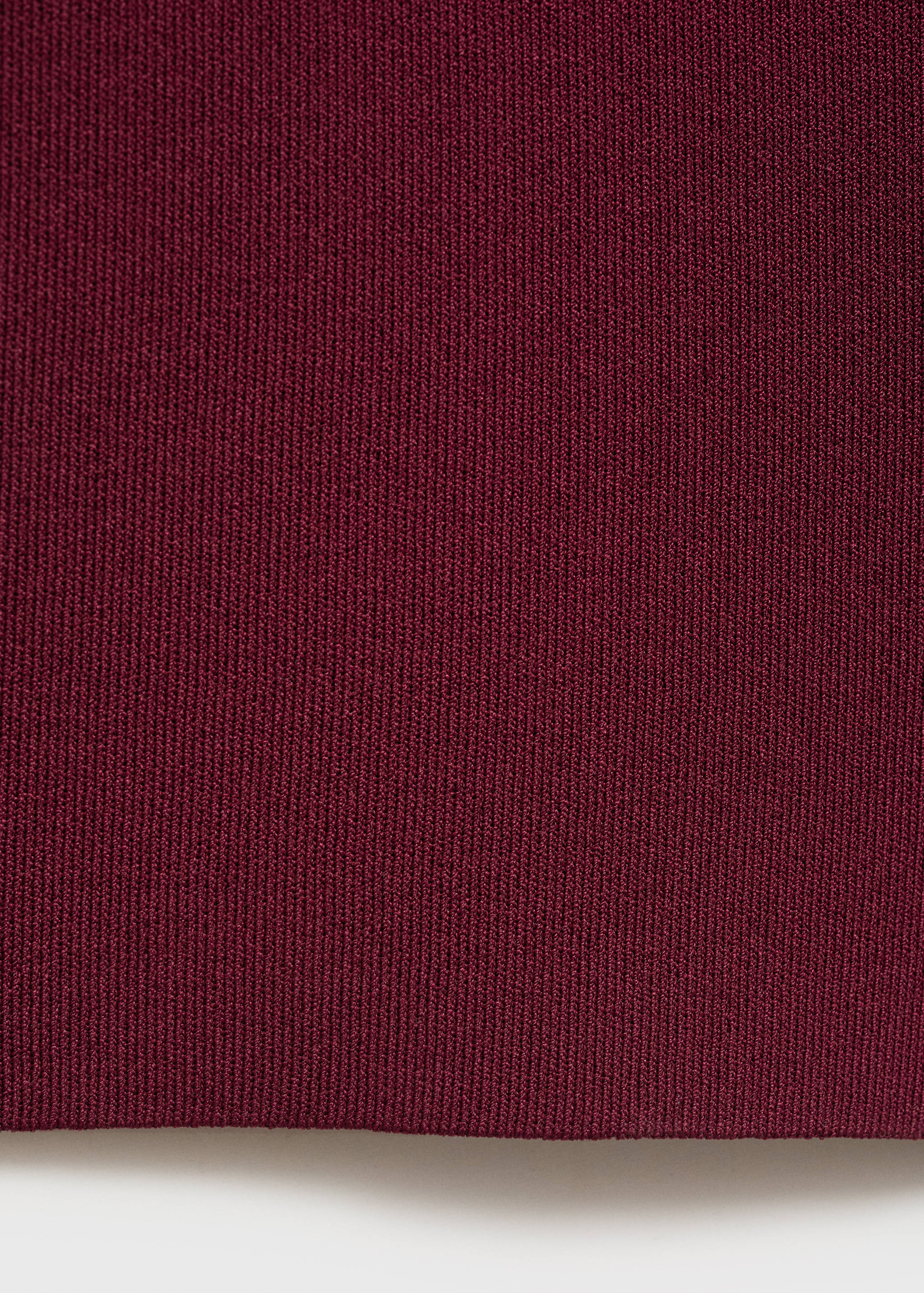 Detalle del tejido de punto acanalado en burdeos de los pantalones.