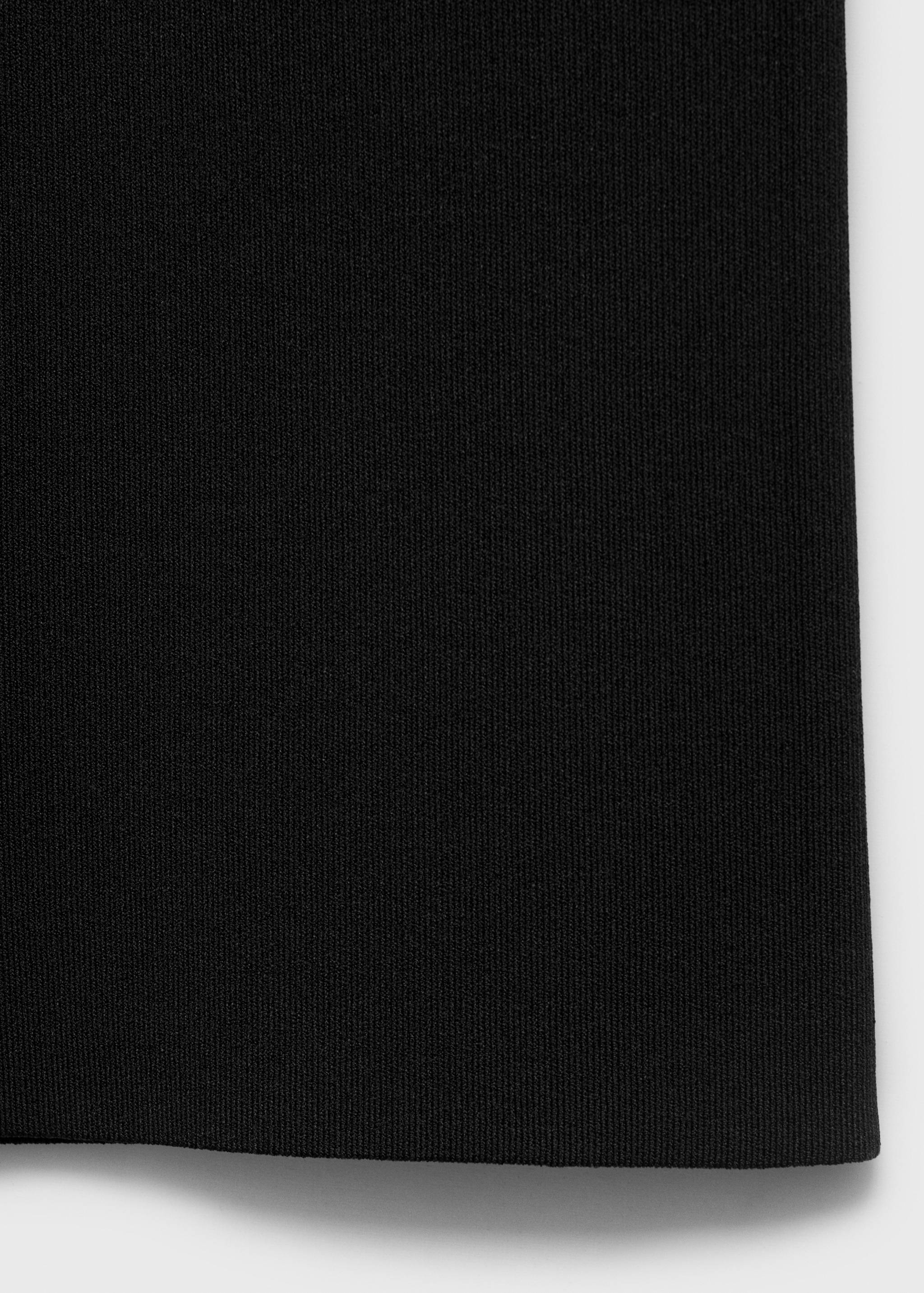 Primer plano de pantalones negros que muestra la textura del tejido de canalé fino.