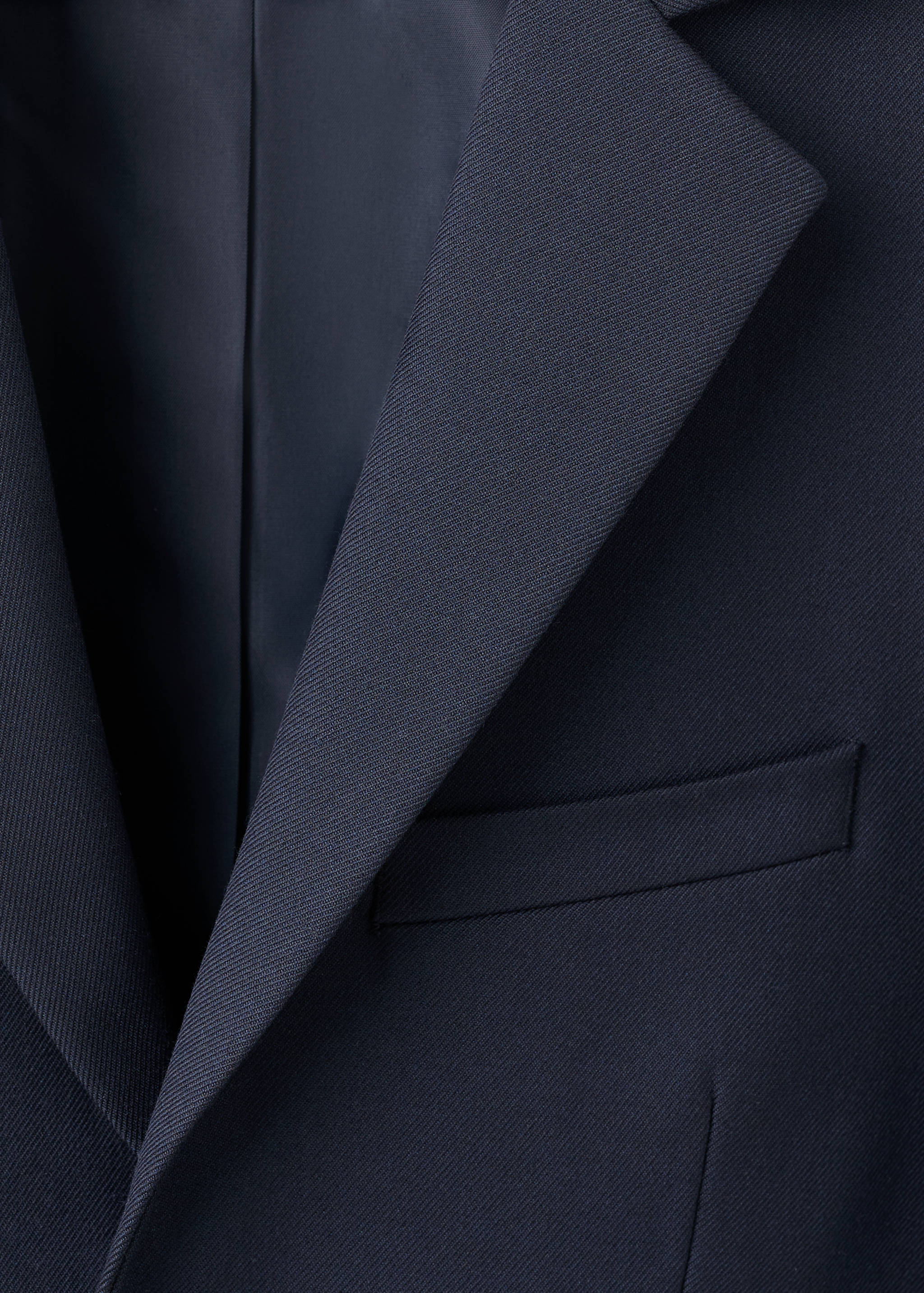 Close-up of a dark navy blue kids' jacket showing the lapel and chest pocket.