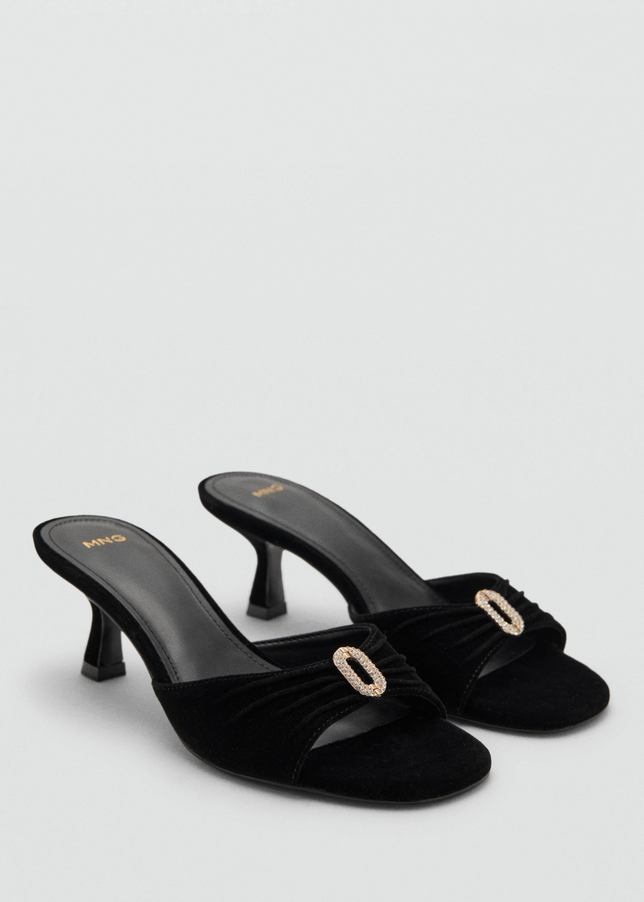 Black heeled mules with gathered front straps and rhinestone buckles.