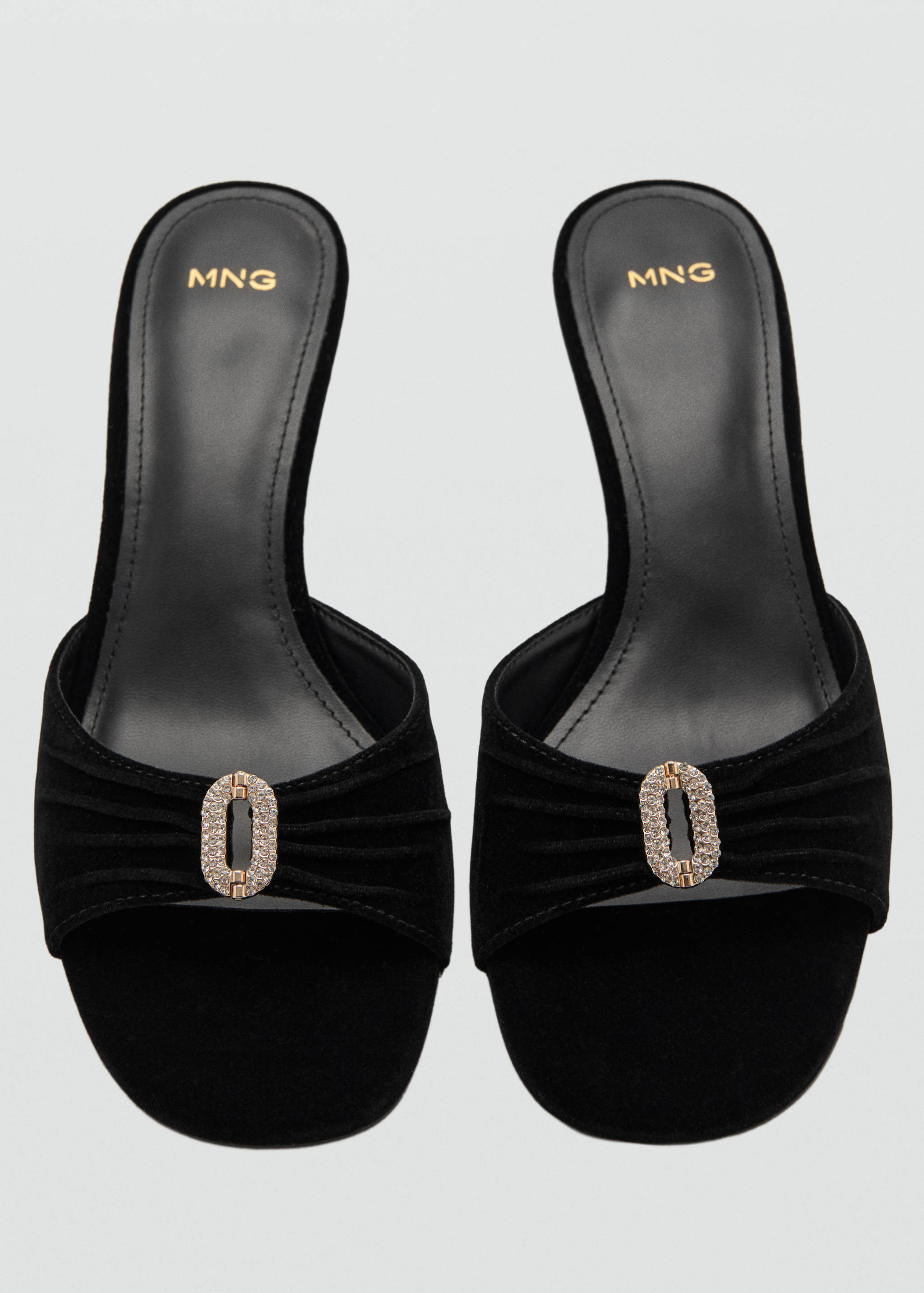 Black velvet mules with a gathered front strap and rhinestone buckle.