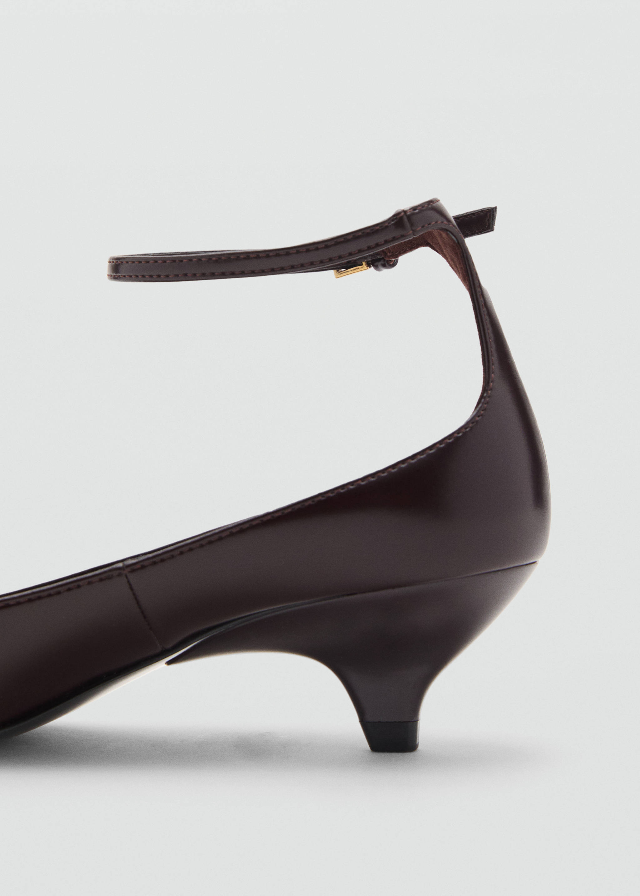 Dark brown shoe close-up featuring a low heel and ankle strap.