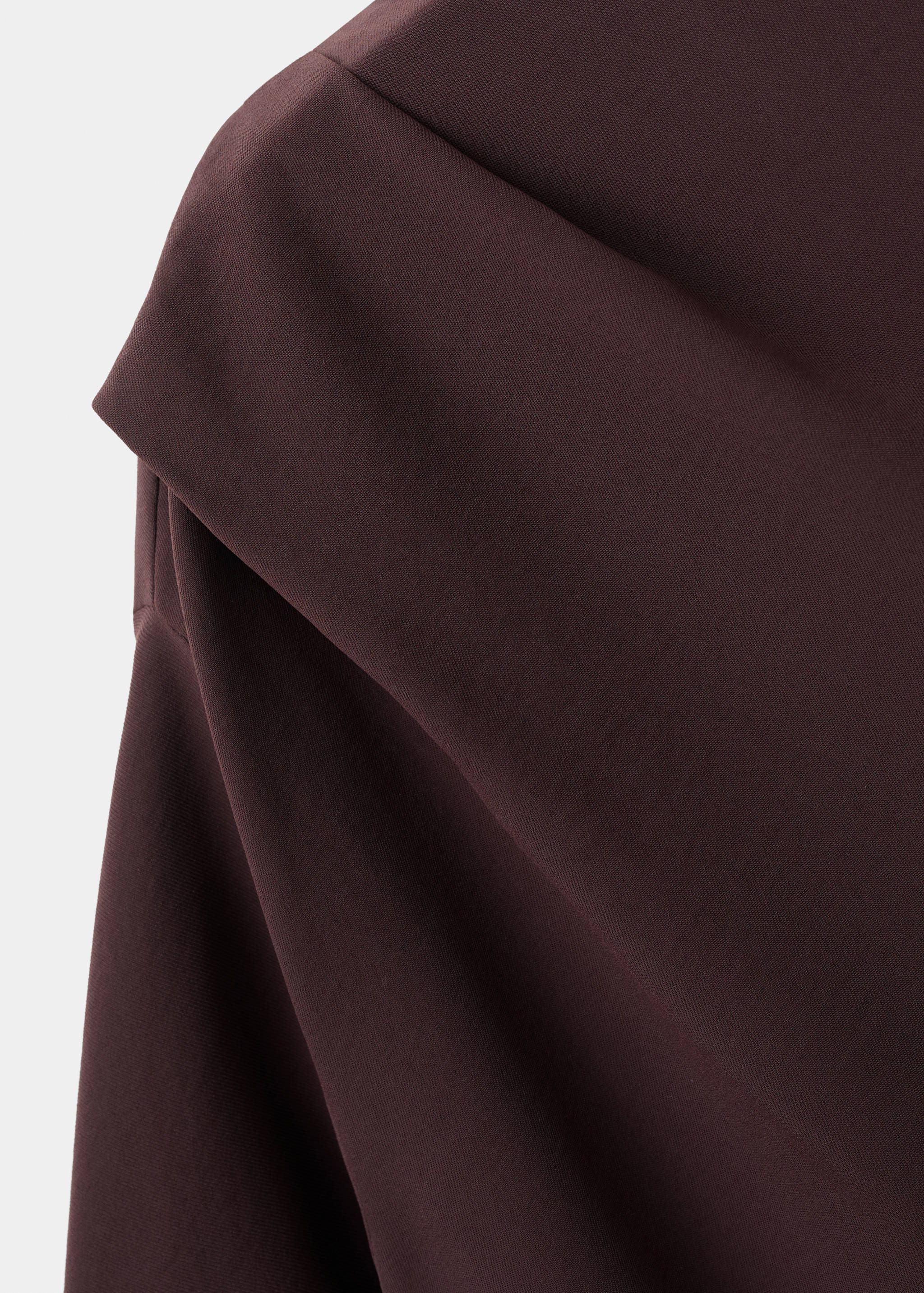 Close-up of a dark brown blouse showing draped shoulder construction.