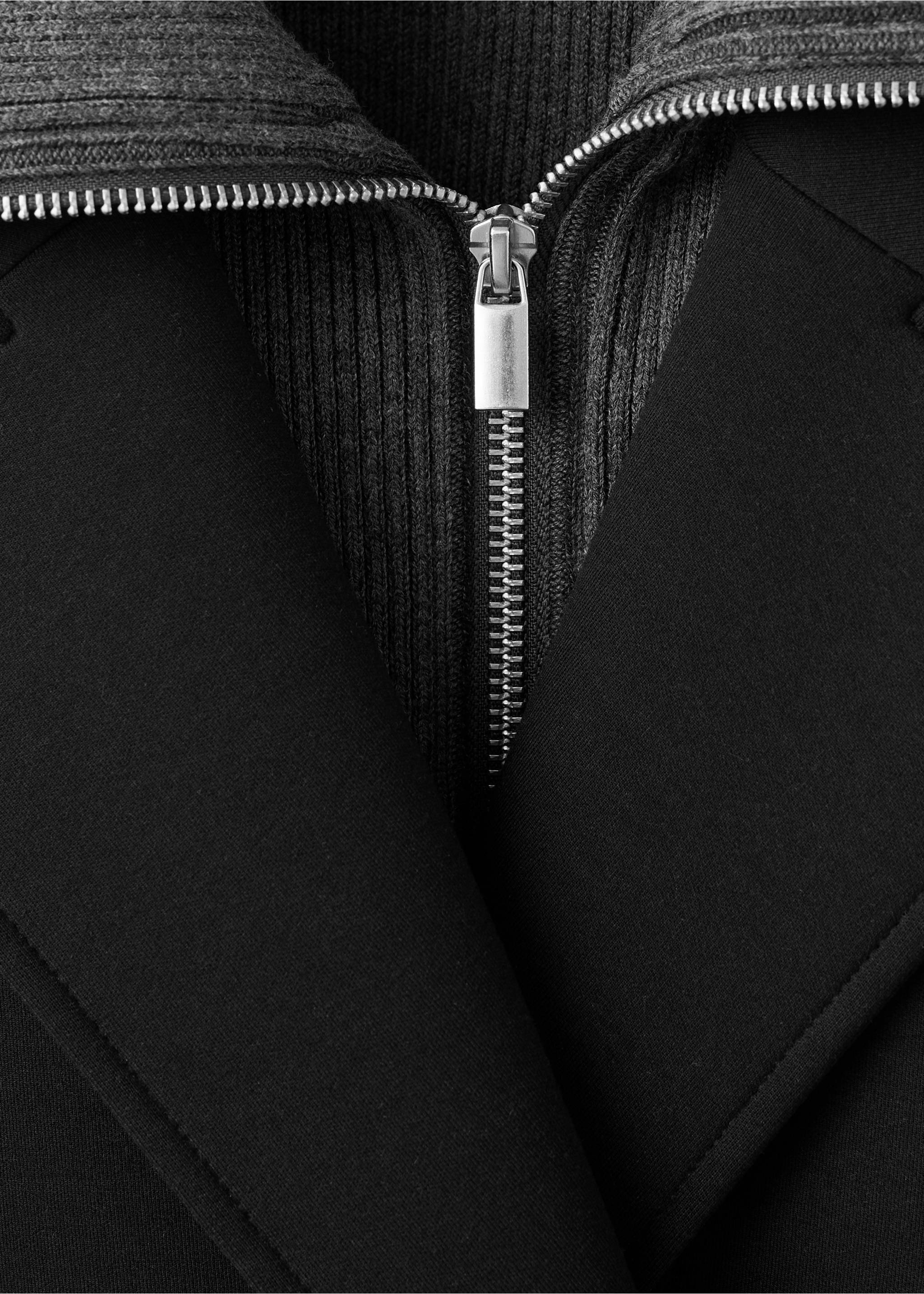Close-up of a black coat with a grey ribbed knit insert and zip., Black. Ref: 17087801-00.