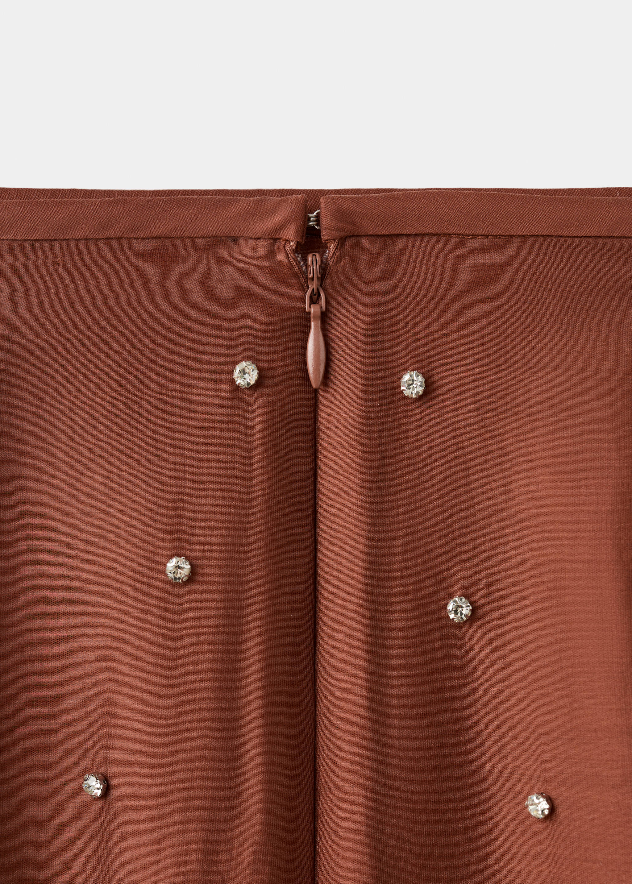 Brown skirt detail showing zip fastening and rhinestone embellishments.