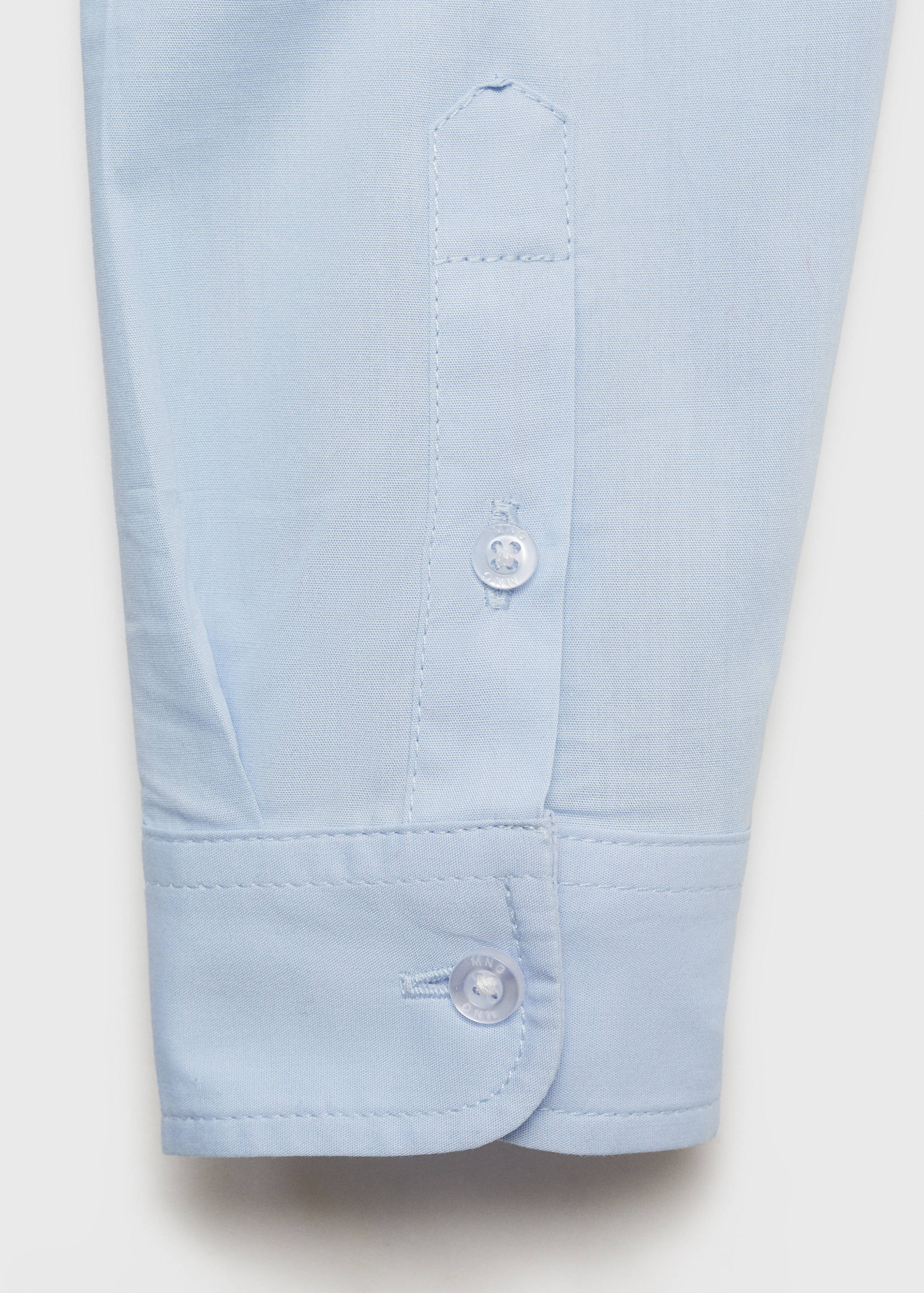 Close-up of the light blue kid's shirt cuff with button detail.