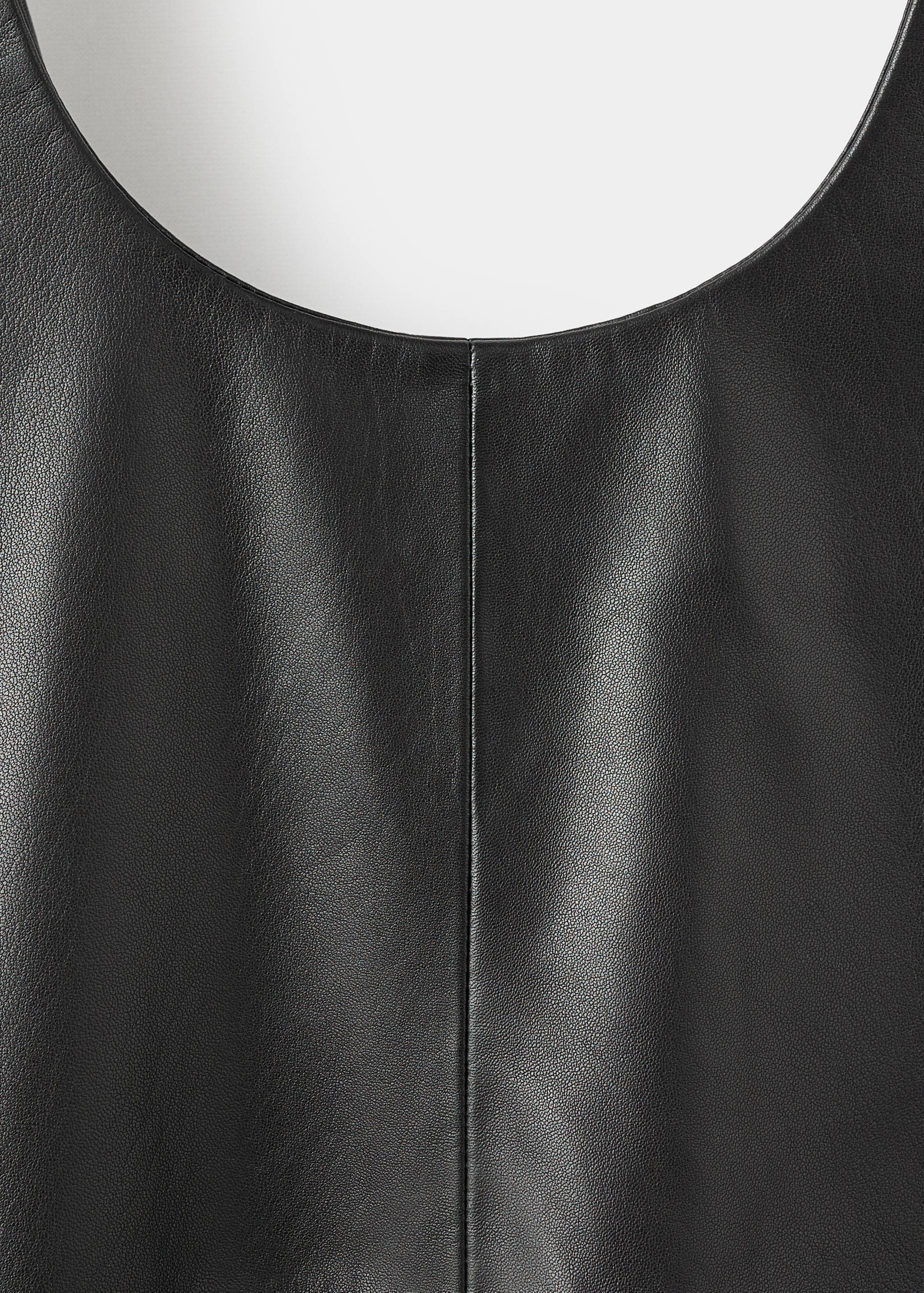 Black leather dress fabric detail showing the texture and neckline.