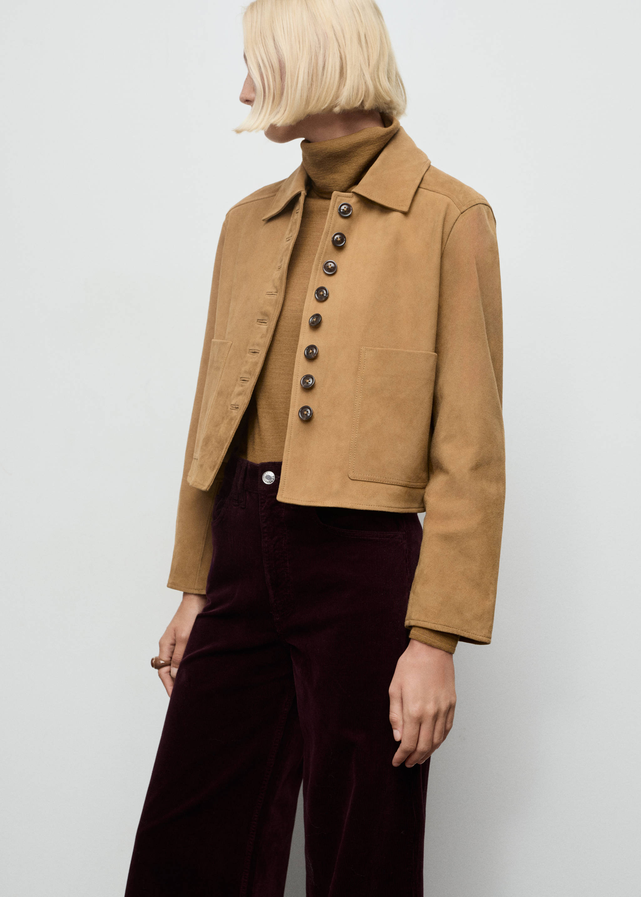 Tan cropped jacket with a collar, long sleeves, and large buttons.