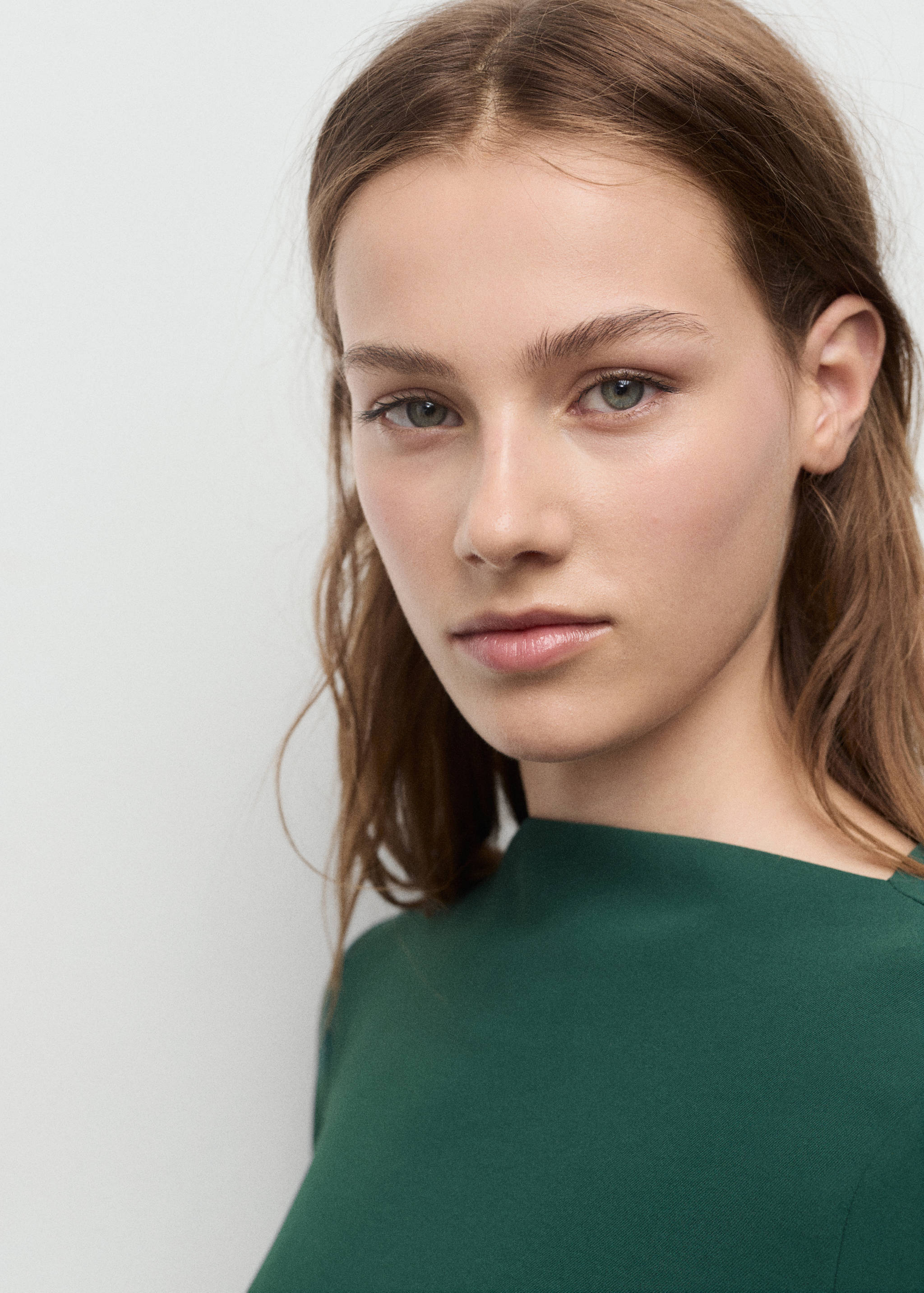 Primer plano de modelo con vestido verde oscuro de cuello barco