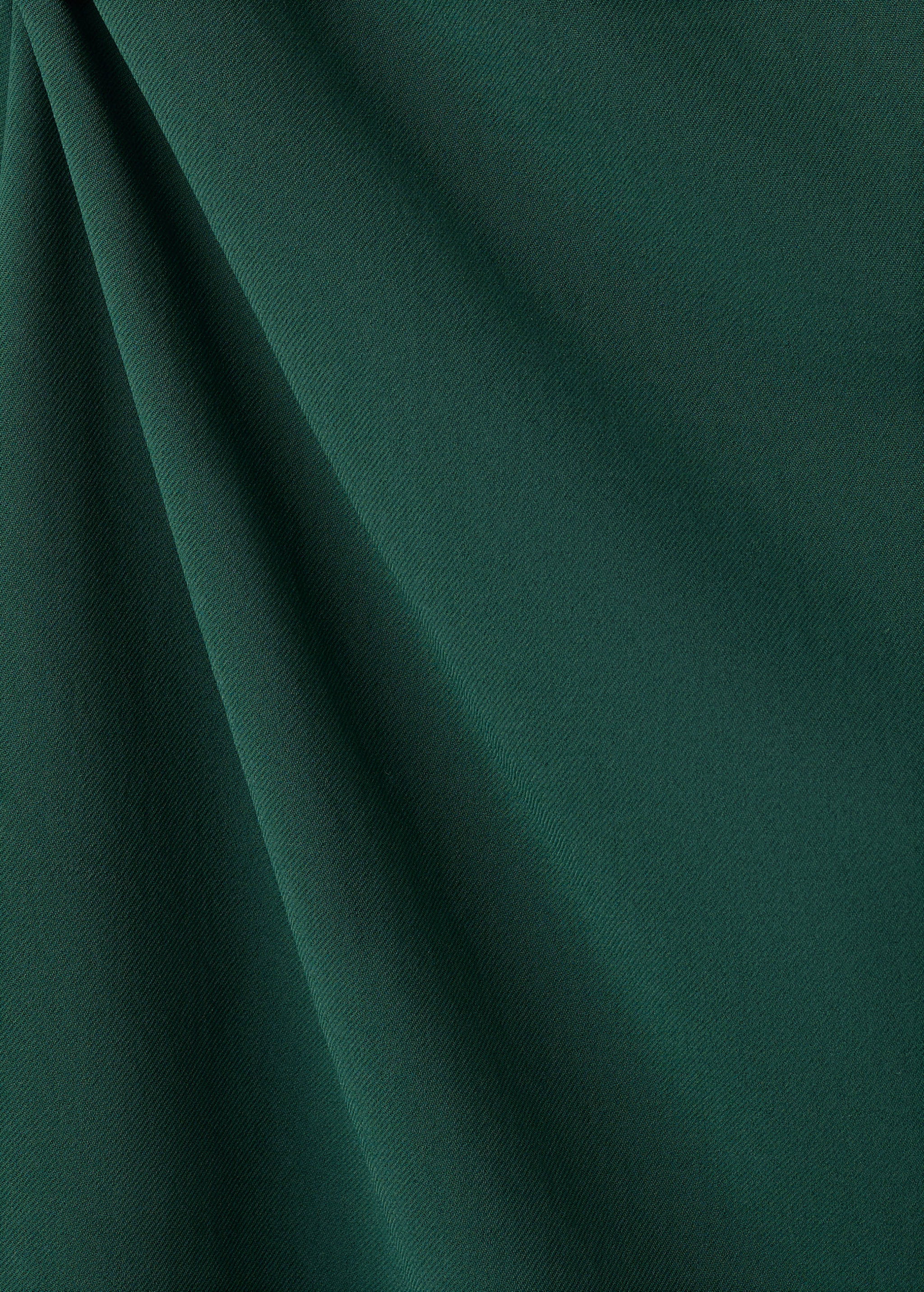 Primer plano del tejido verde oscuro del vestido con pliegues drapeados.