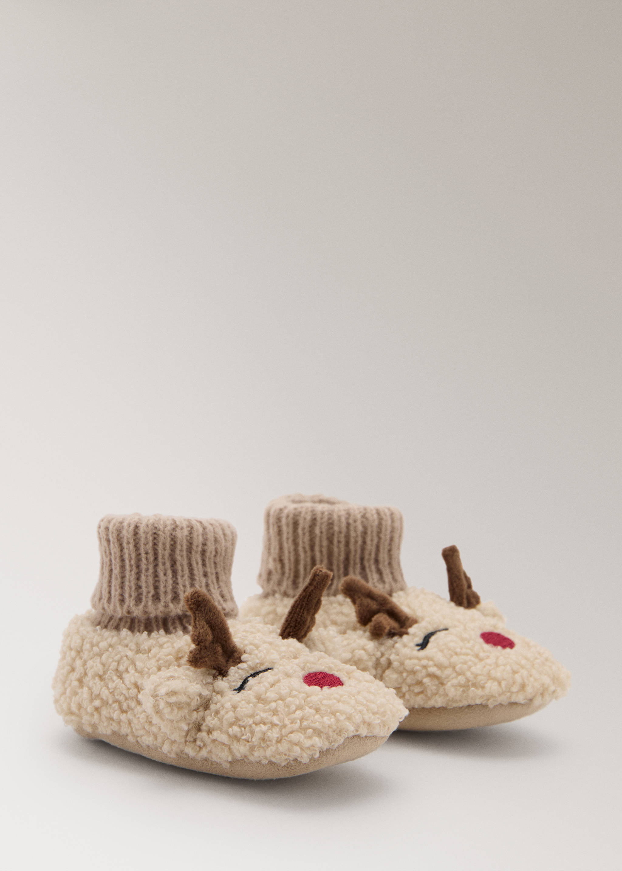 Plush cream reindeer house slippers with brown antlers and ribbed knit cuffs.