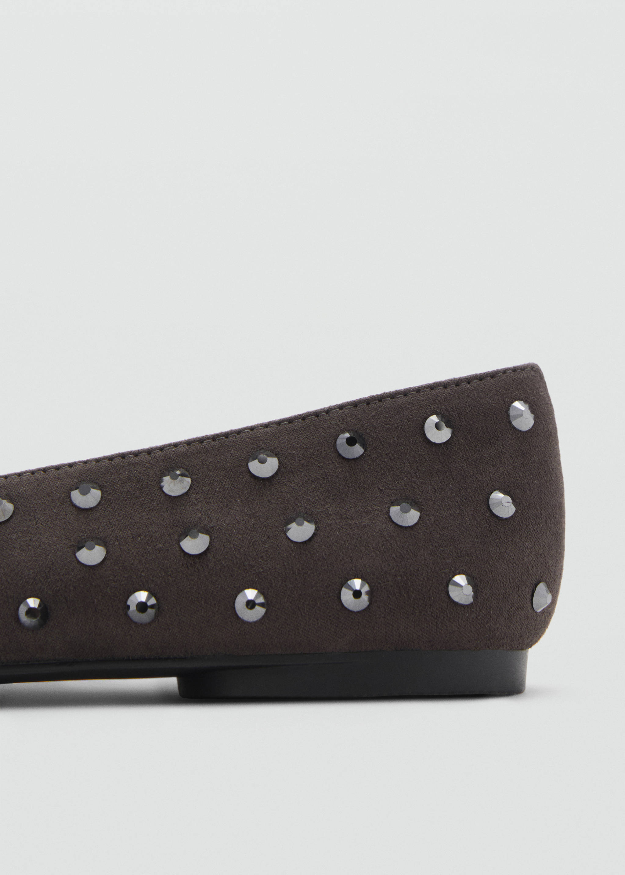 Close-up of a dark grey flat shoe detailed with metallic studs.