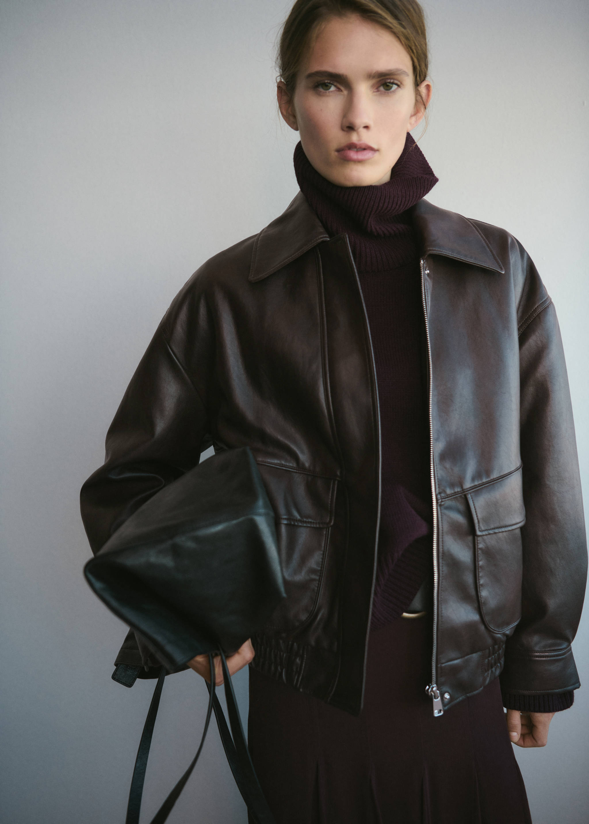 Dark brown leather bomber jacket with a pointed collar and front flap pockets.