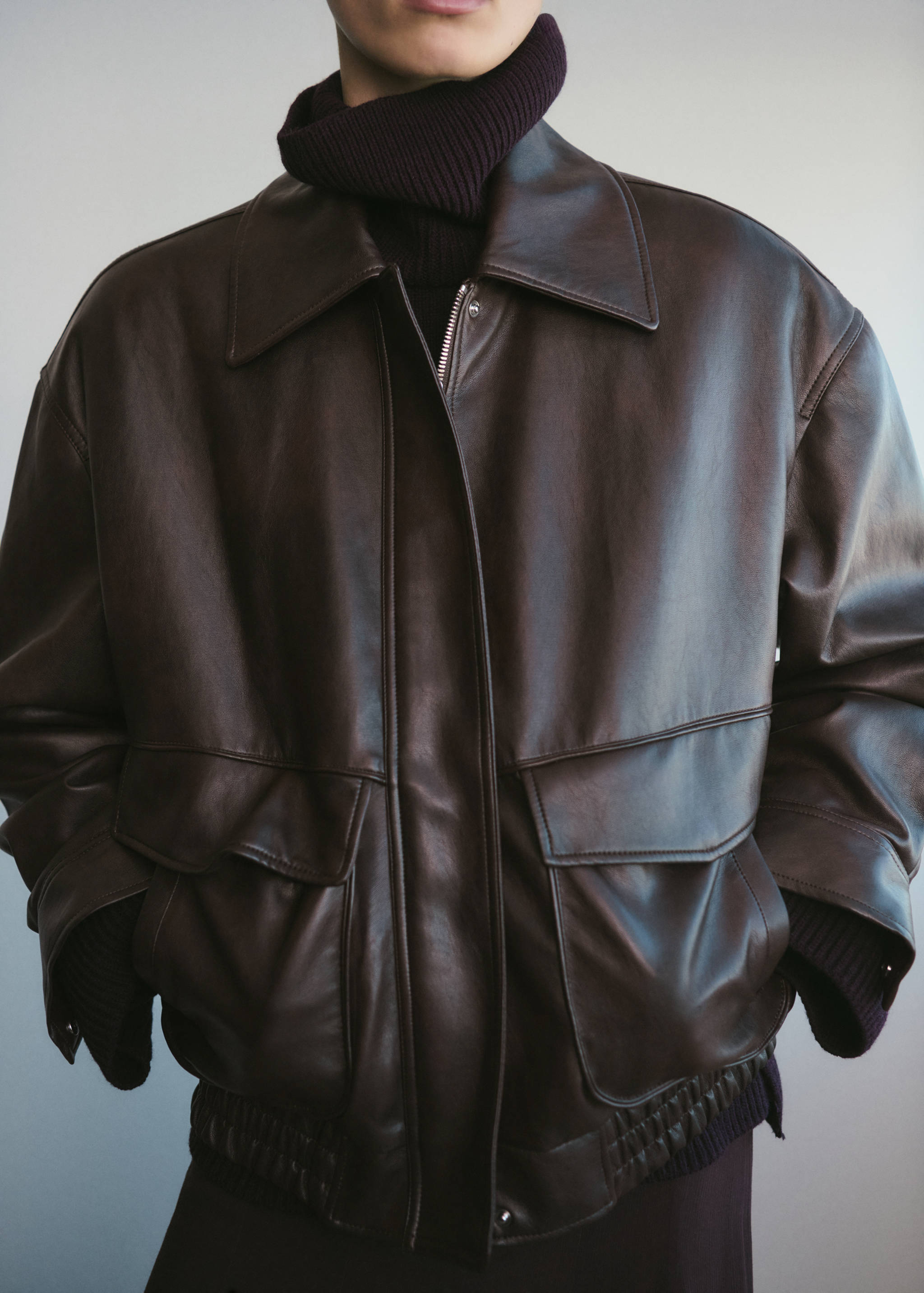 Dark brown oversized jacket with a collar, front flap pockets, and a zip fastening.