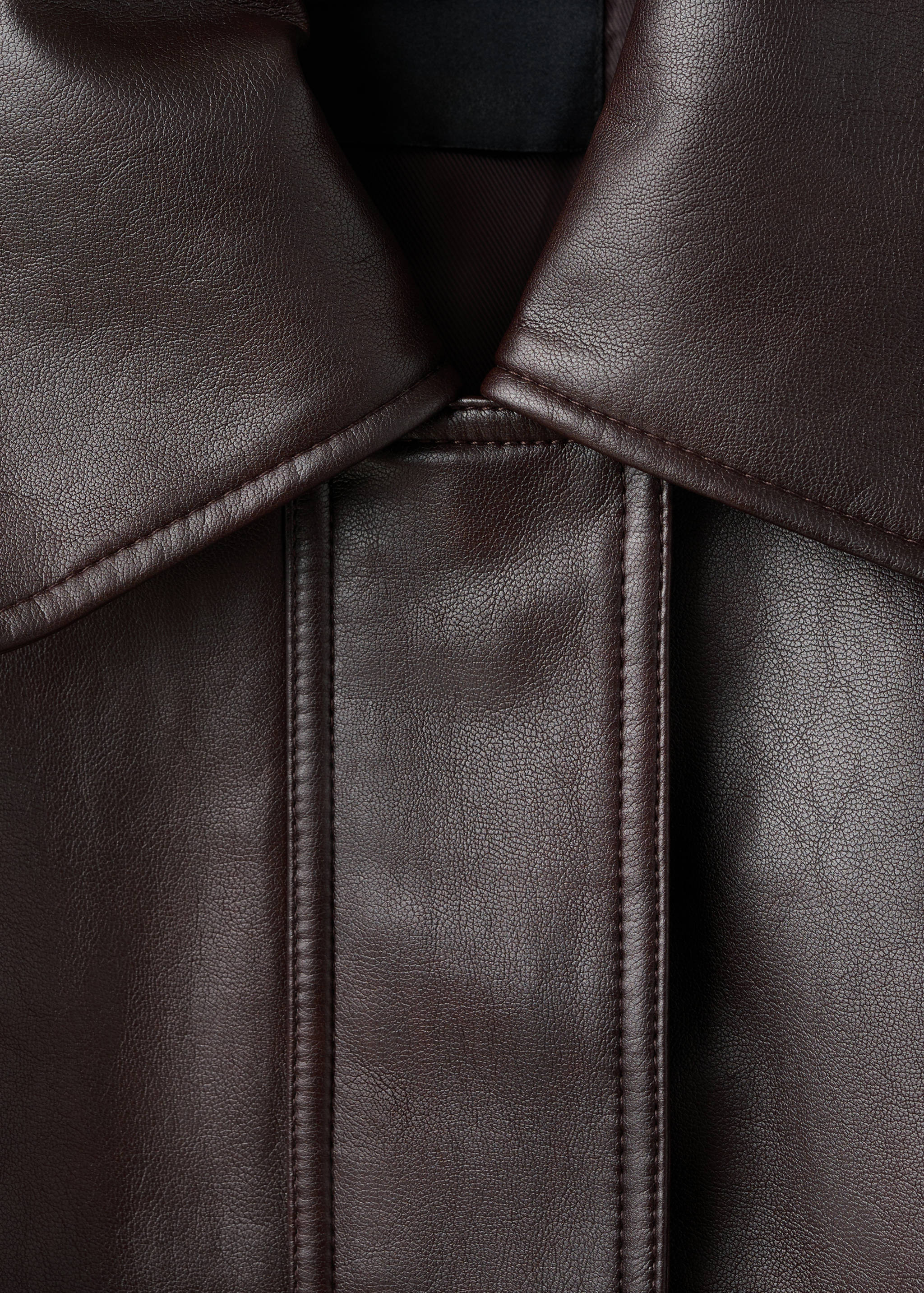 Close-up of a dark brown jacket collar and panel stitching.