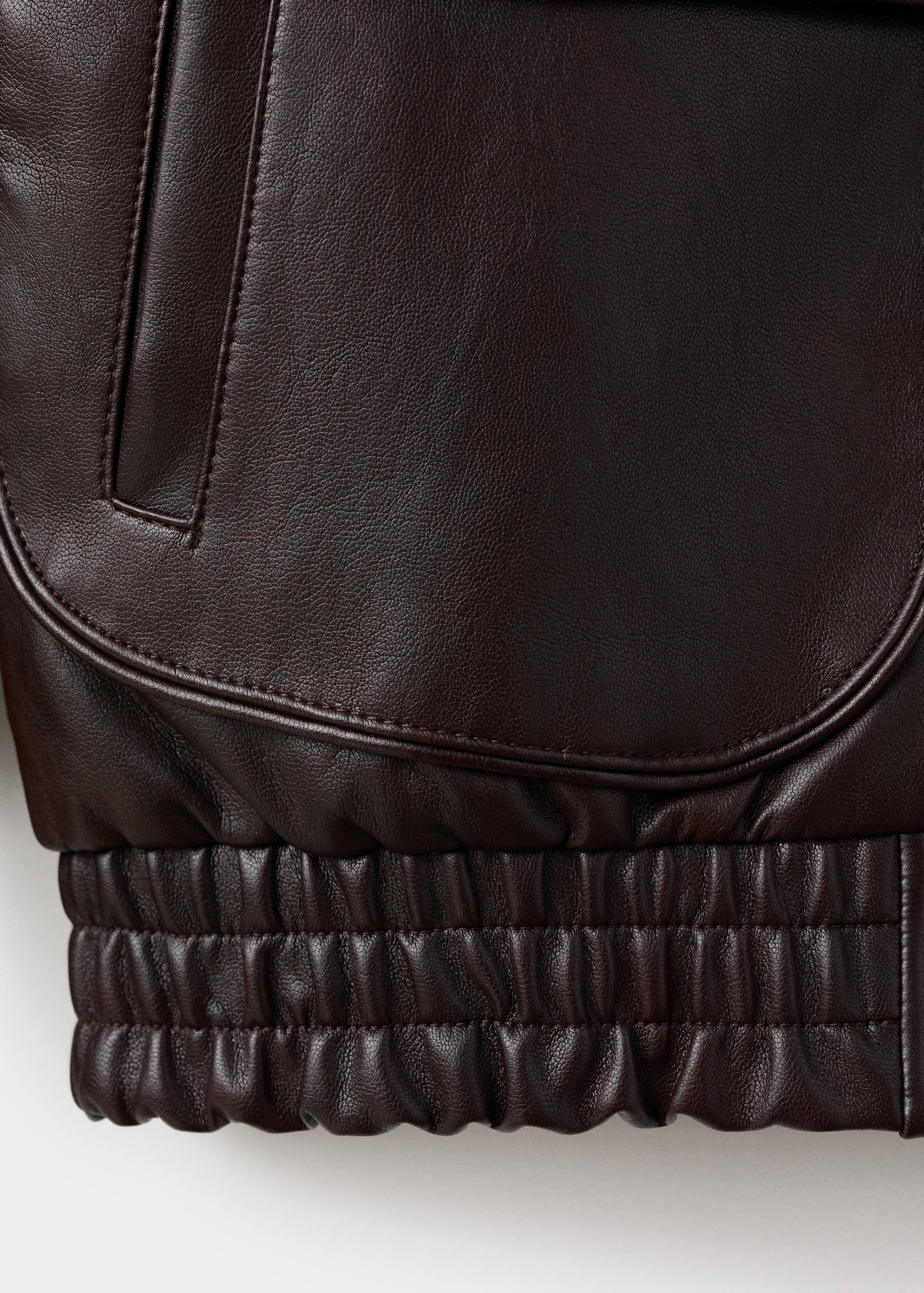 Dark brown jacket texture detail showing the elasticated hem and pocket.