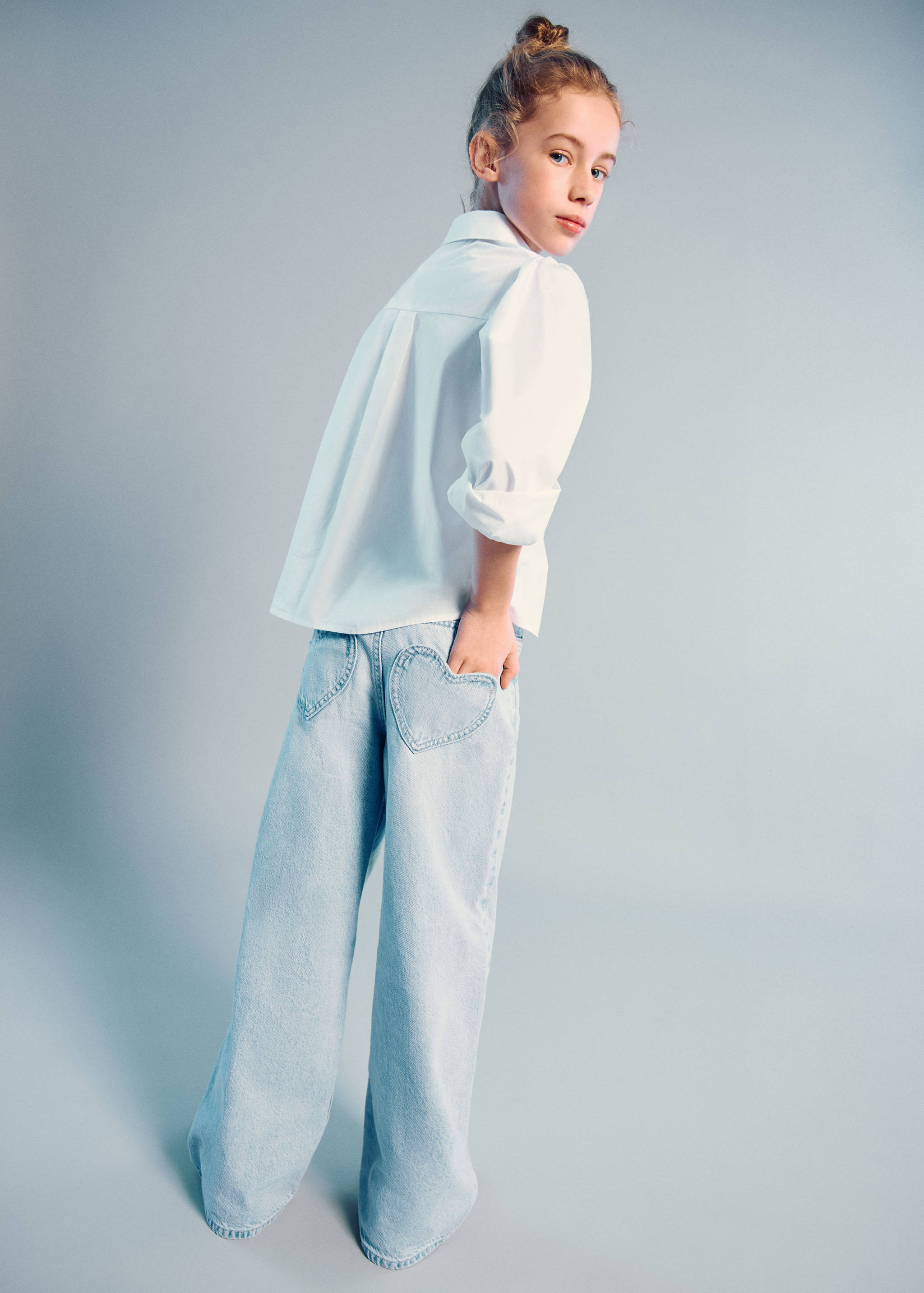 Light-blue denim trousers with heart-shaped back pockets, worn with a white shirt.