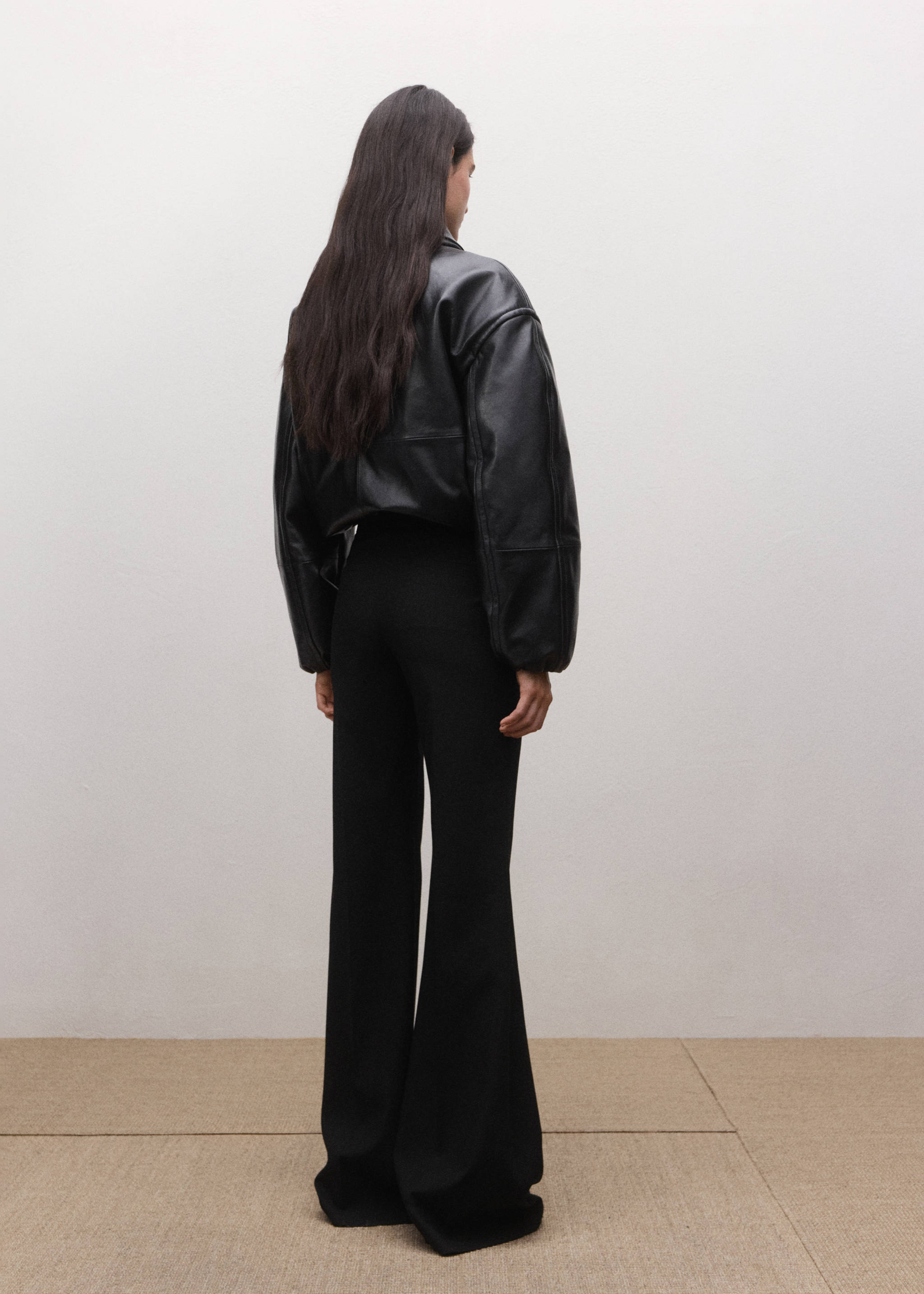 Back view of black trousers with a flared hem.