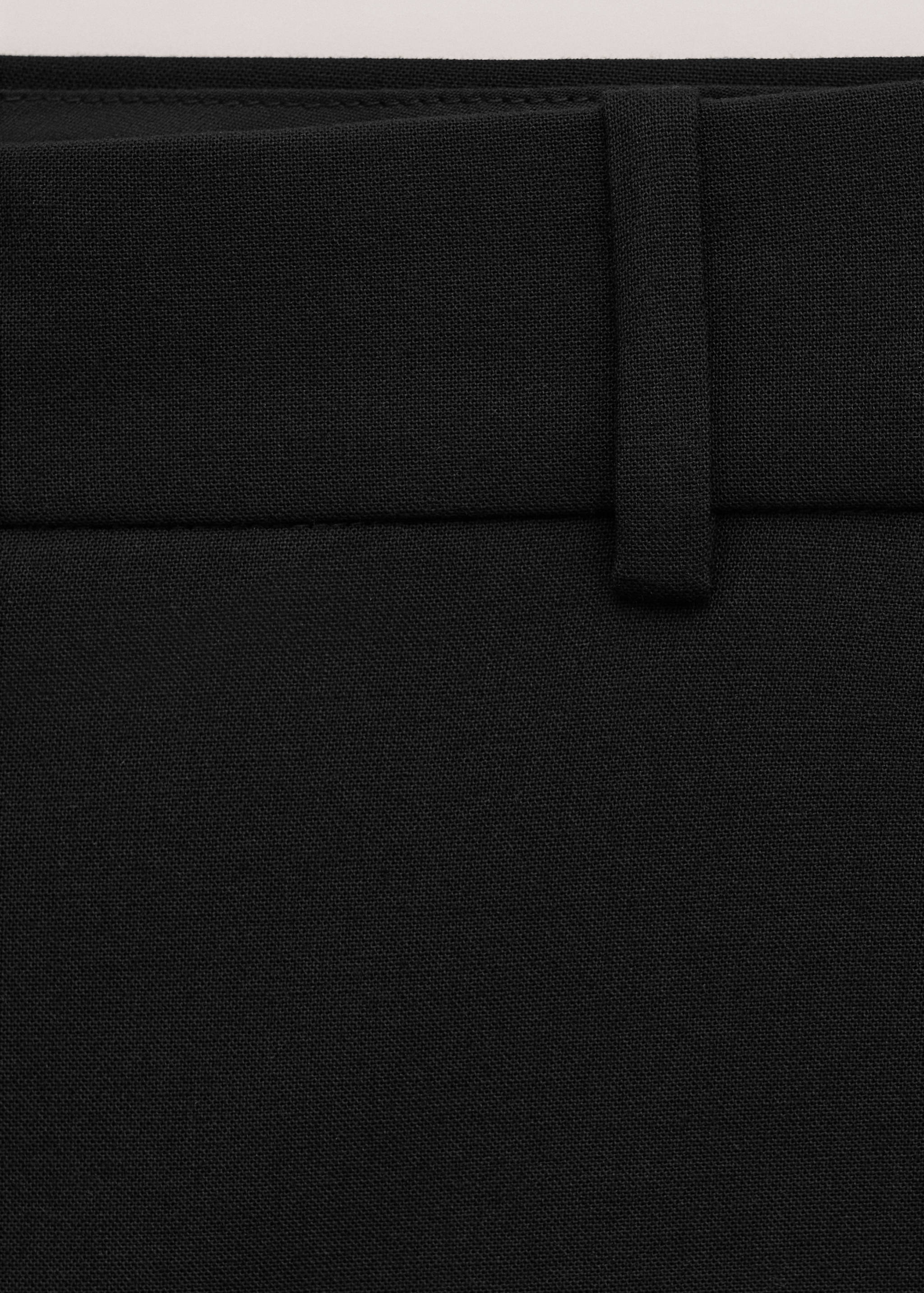 Close-up of black trousers showing the fabric texture and waistband detail.