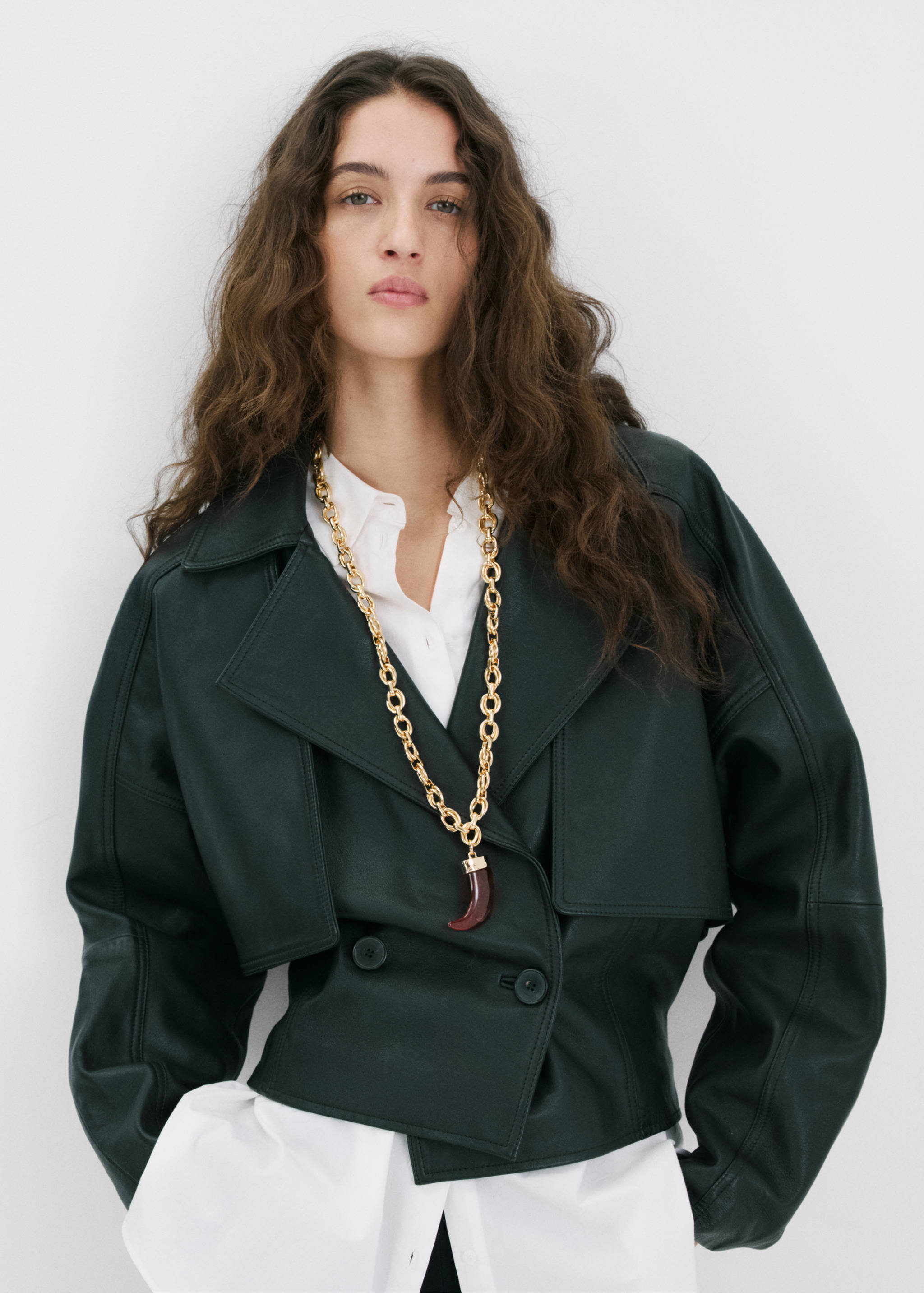 Long gold-tone chain necklace with a reddish-brown horn pendant worn on a model.