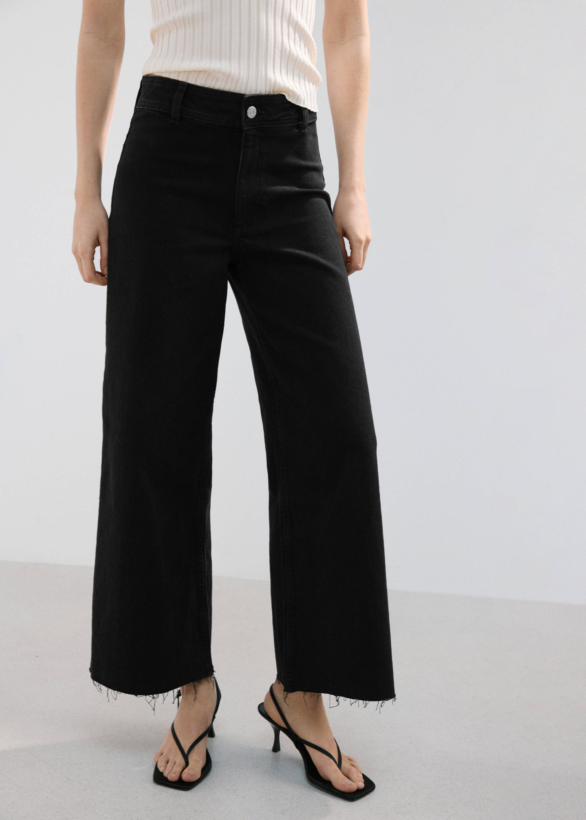 Black high-waist denim trousers with a raw frayed hem.