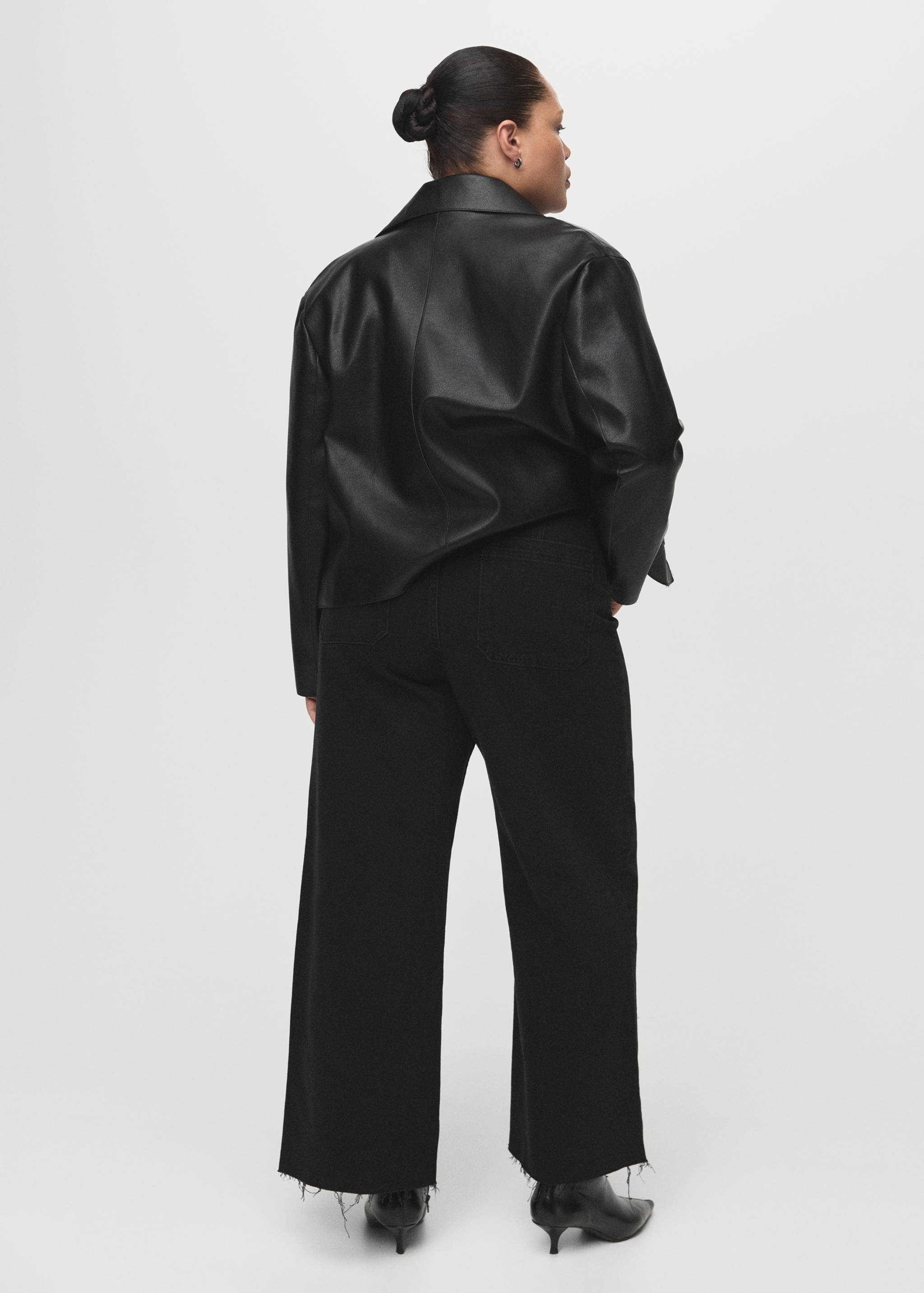 Black wide-leg denim trousers with frayed hems, back view.