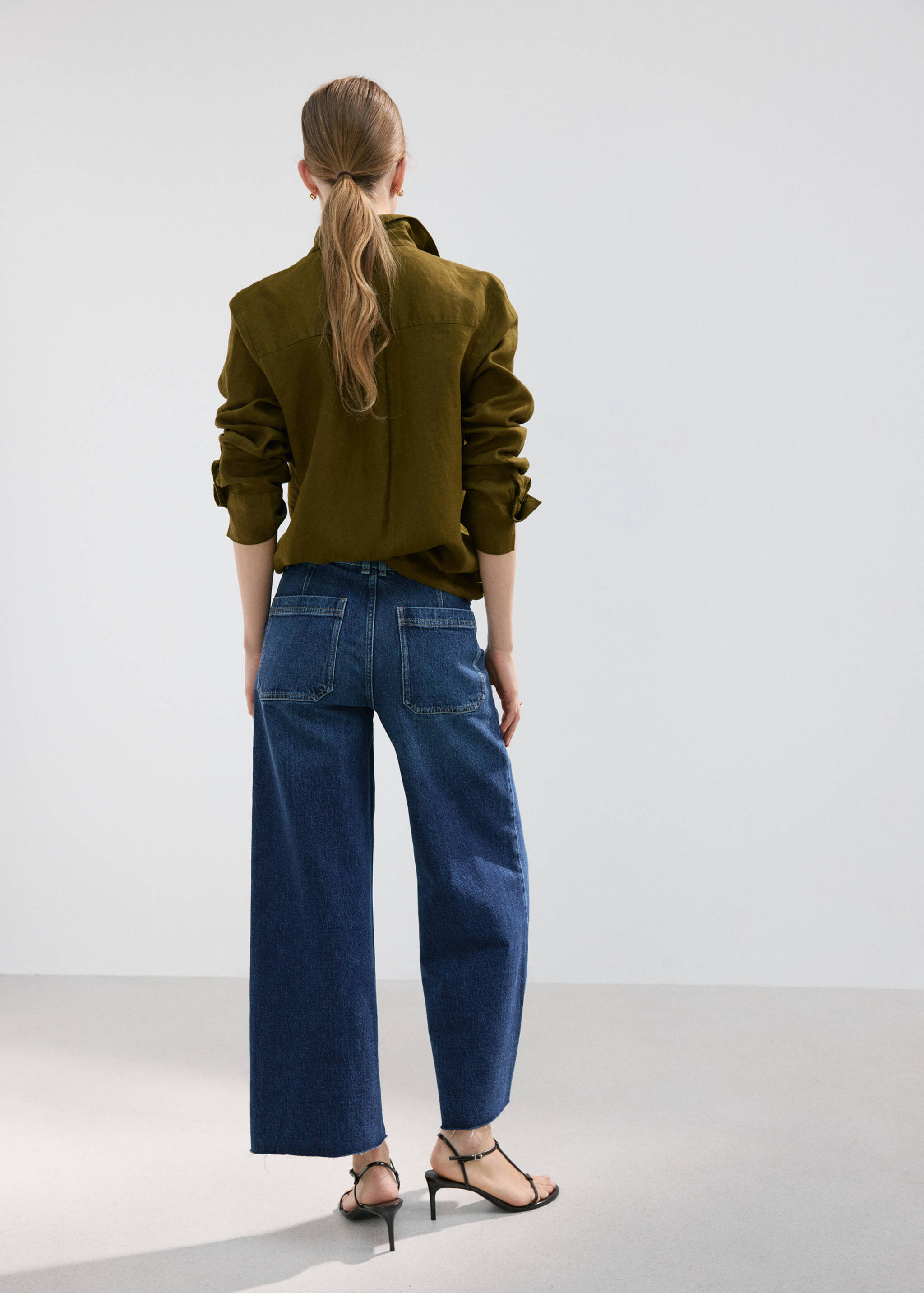 Dark blue denim trousers with wide-leg fit and back pockets, back view.