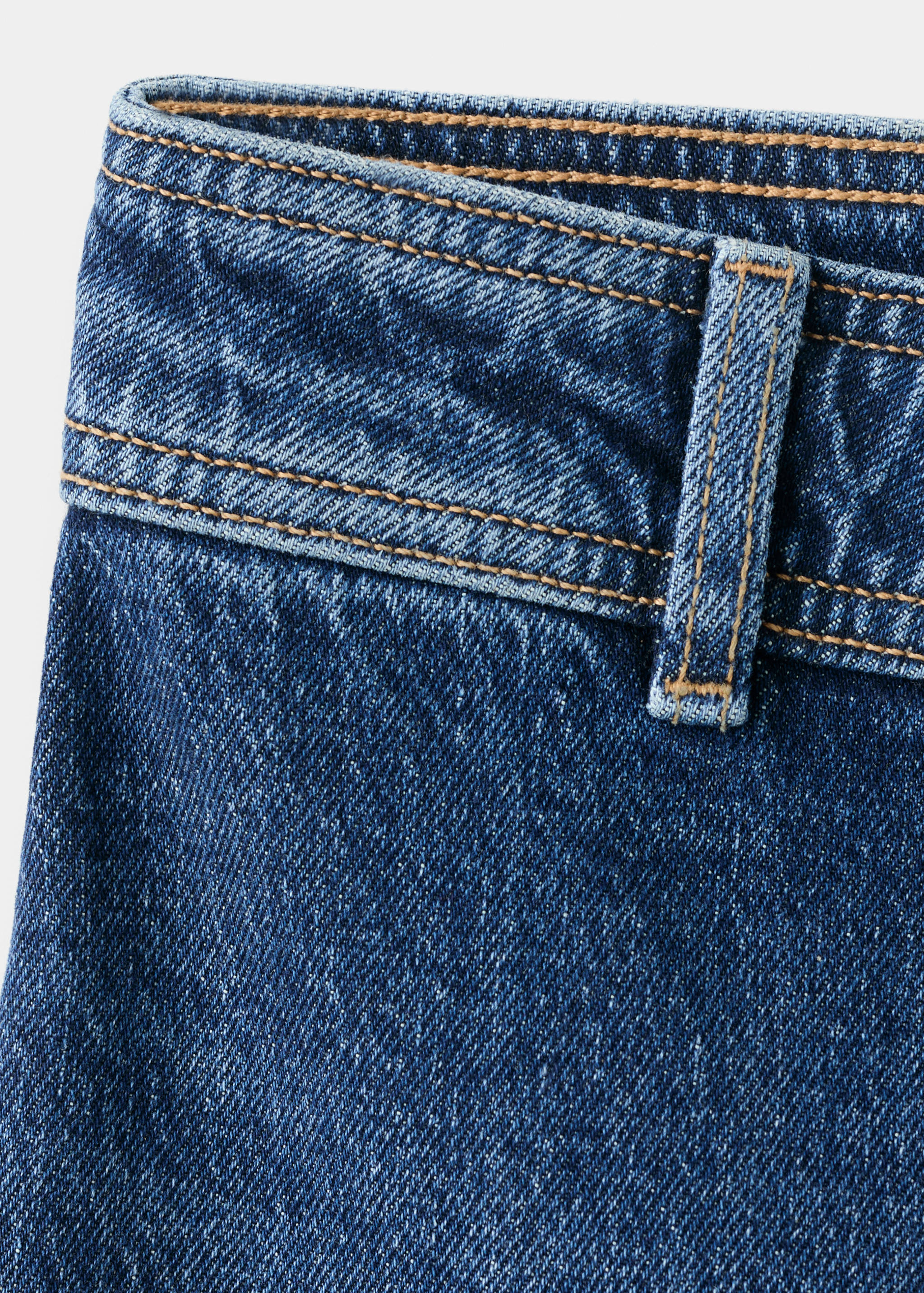 Close-up of blue denim trousers, focusing on the waistband and belt loop.