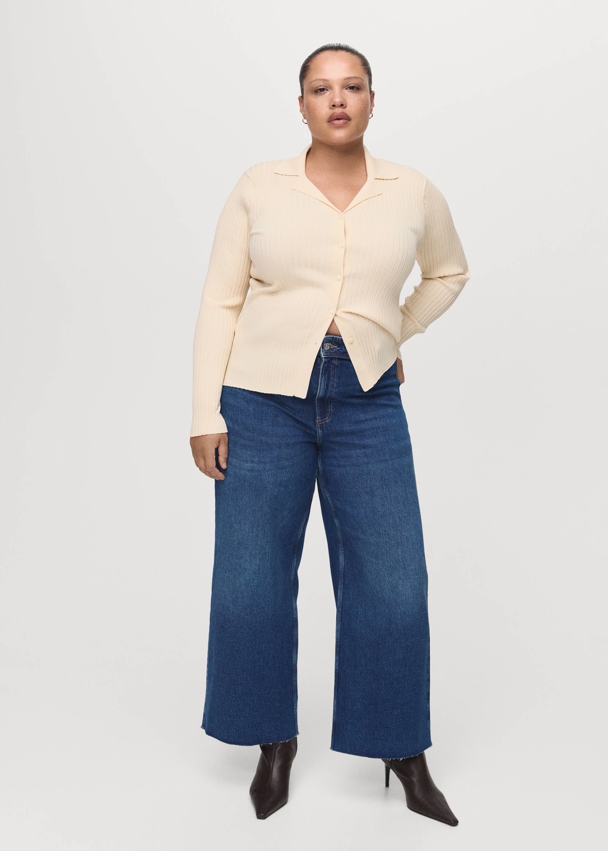 Blue denim trousers worn with a cream ribbed knit cardigan.