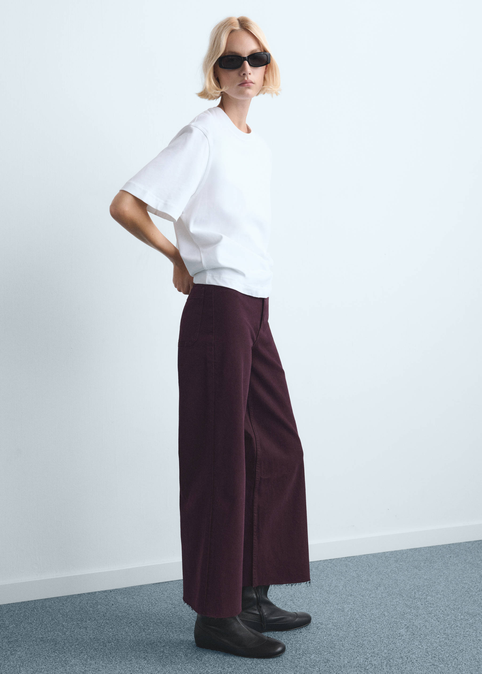 Dark plum wide-leg denim trousers with a raw hem, styled with a white t-shirt.