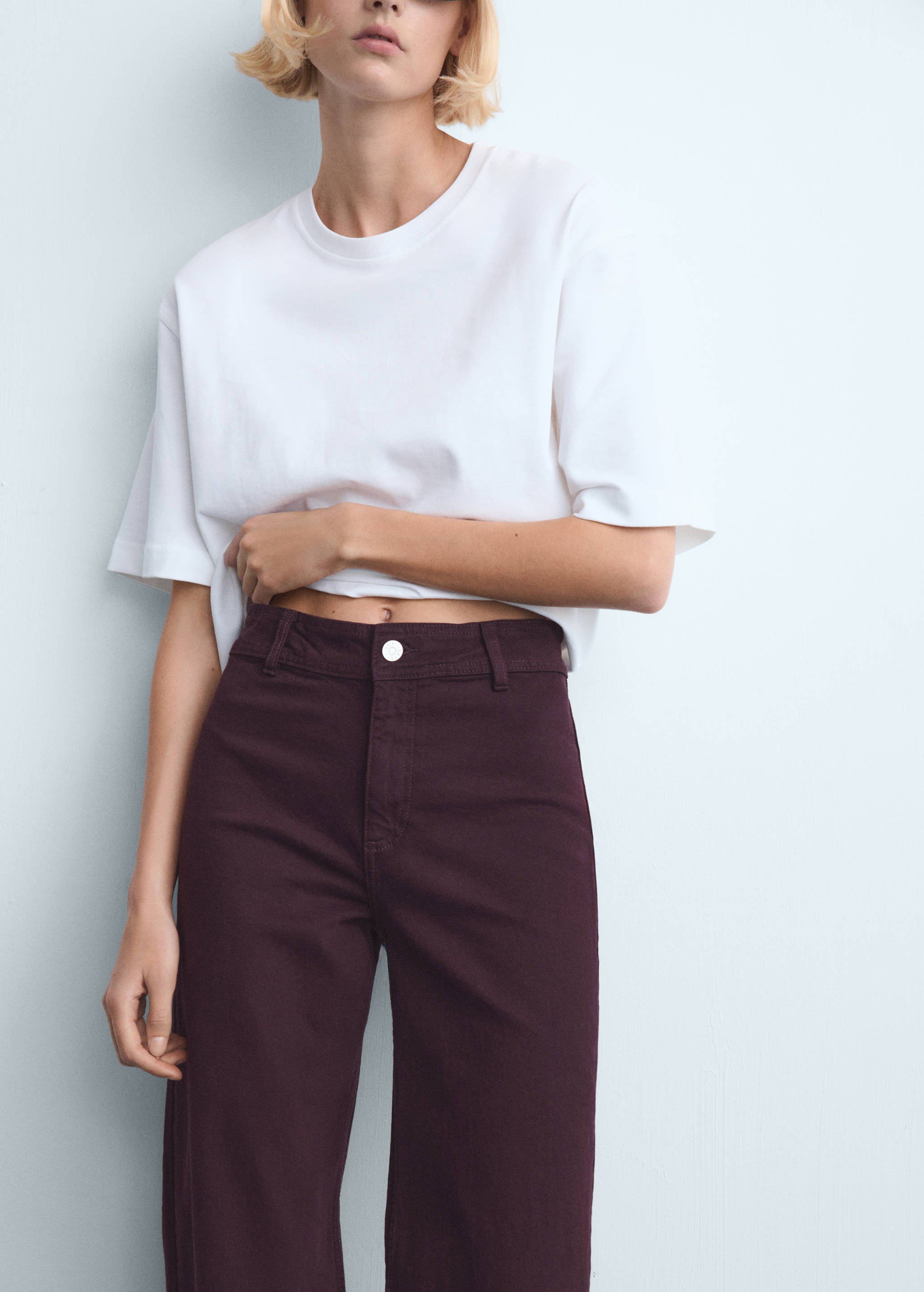High-waisted dark burgundy denim trousers worn with a white t-shirt