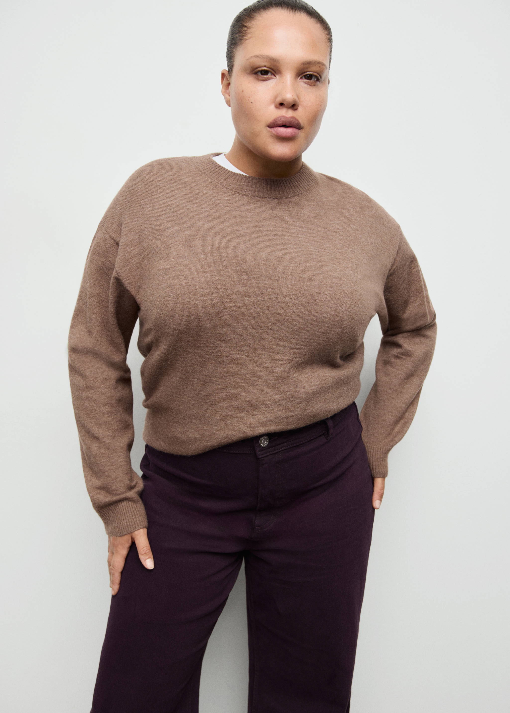 Dark purple denim trousers worn with a brown knitted jumper.