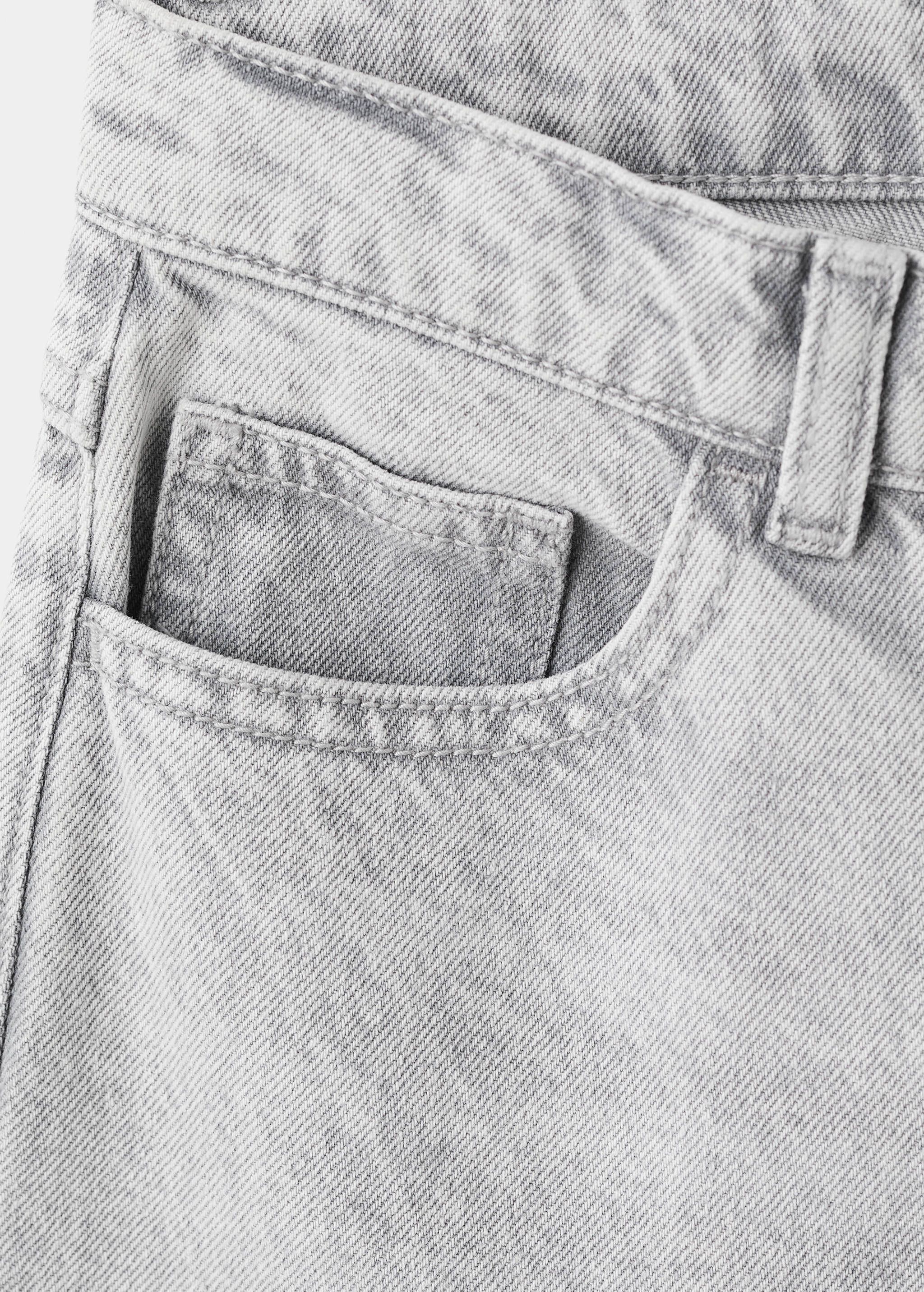 Close-up of light grey denim trousers featuring coin pocket detail.