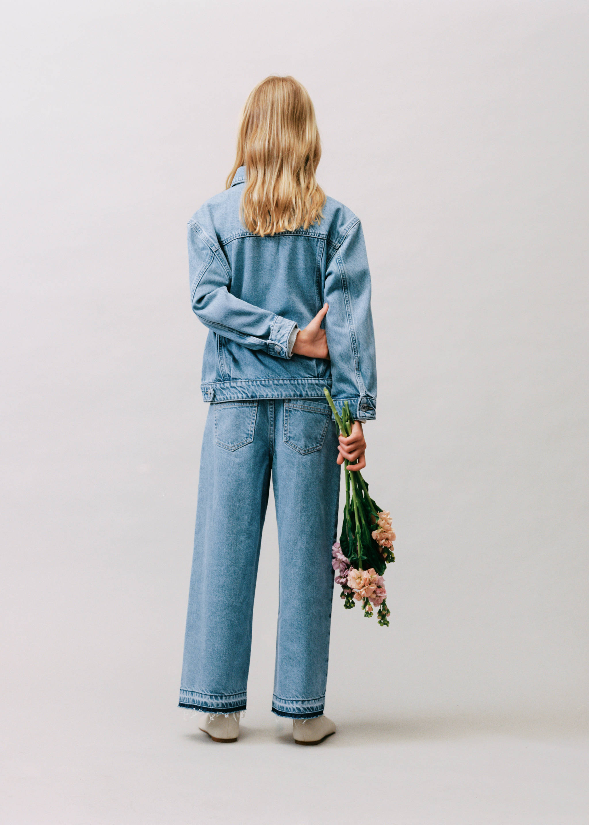 Light blue denim culotte trousers with wide legs and raw hems, back view.