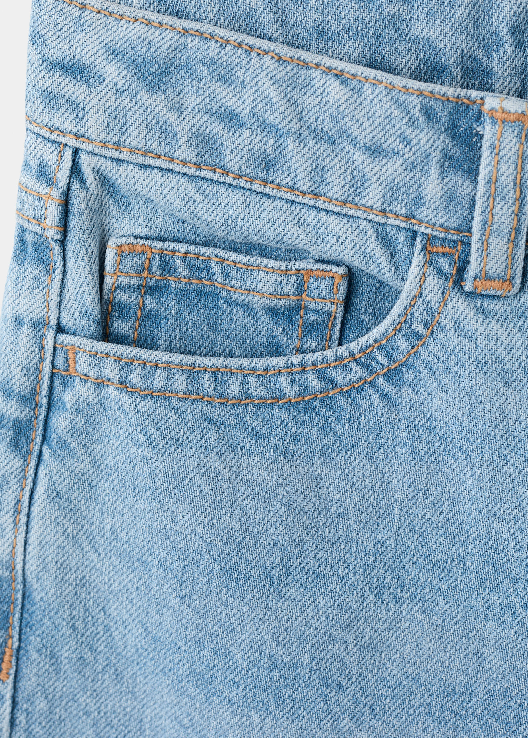 Close-up of light blue denim trousers featuring contrast topstitching.