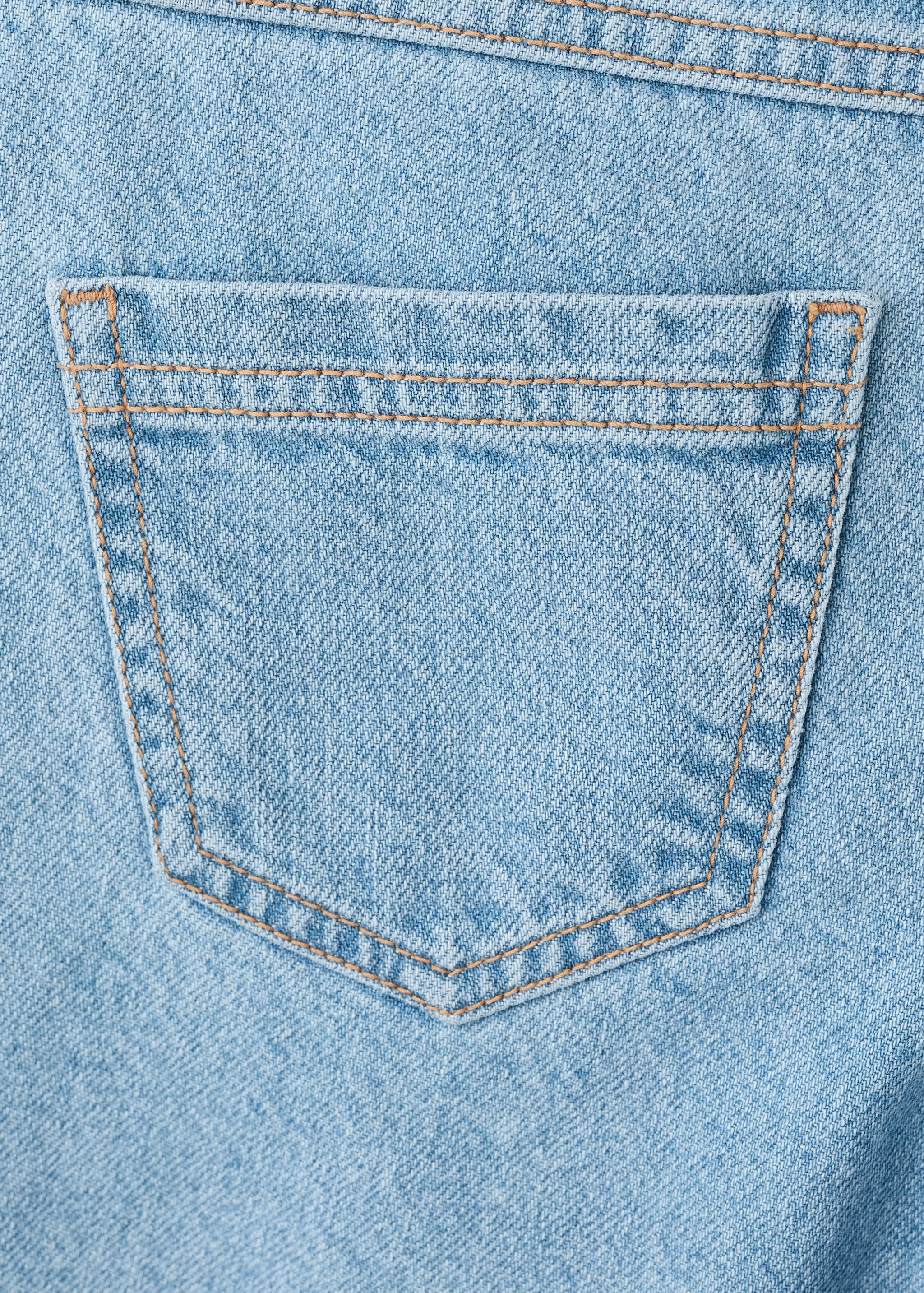 Close-up of light blue denim culotte trousers focusing on the back pocket and contrast stitching.