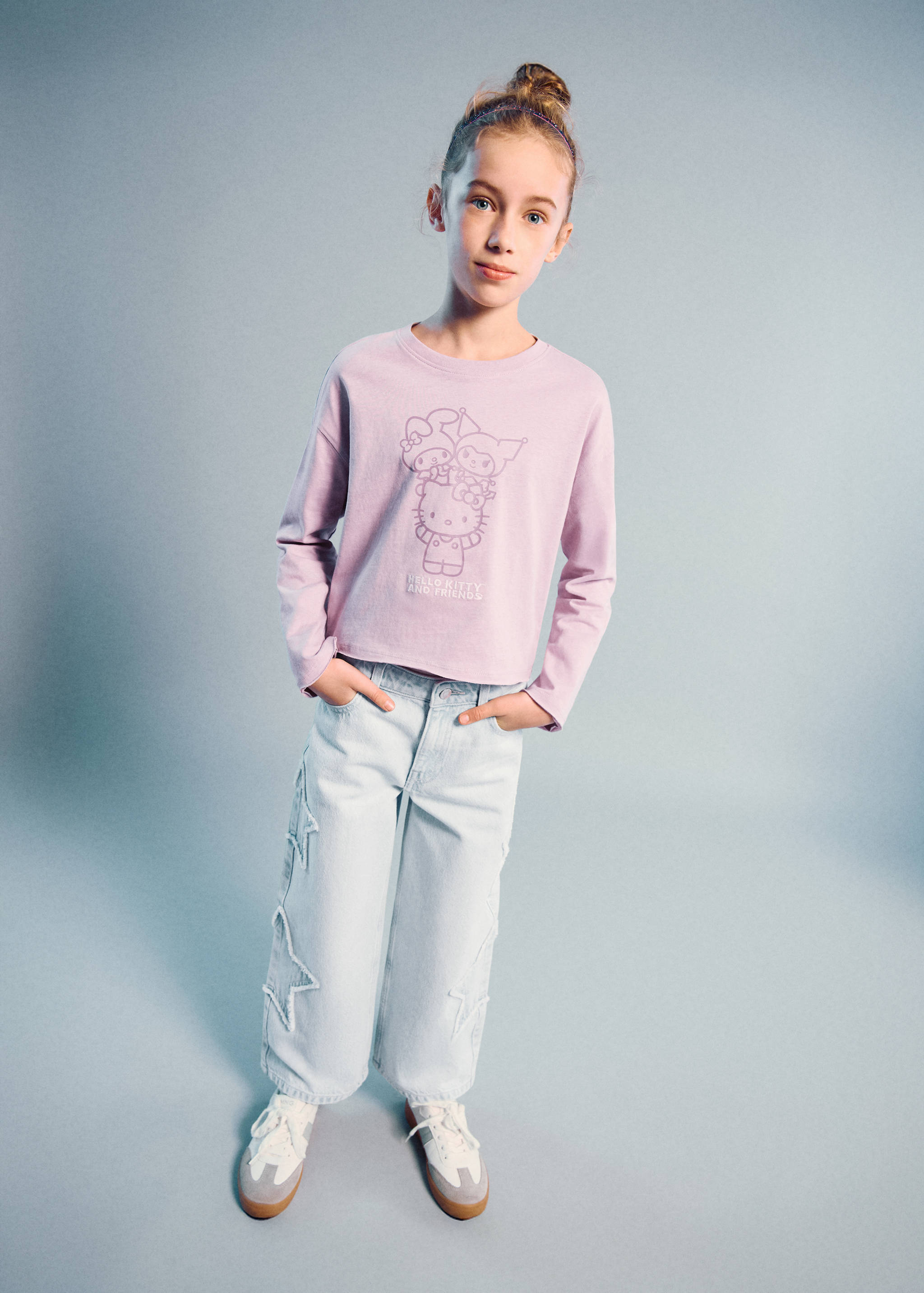 Light wash denim trousers with frayed star details, worn with a graphic t-shirt.