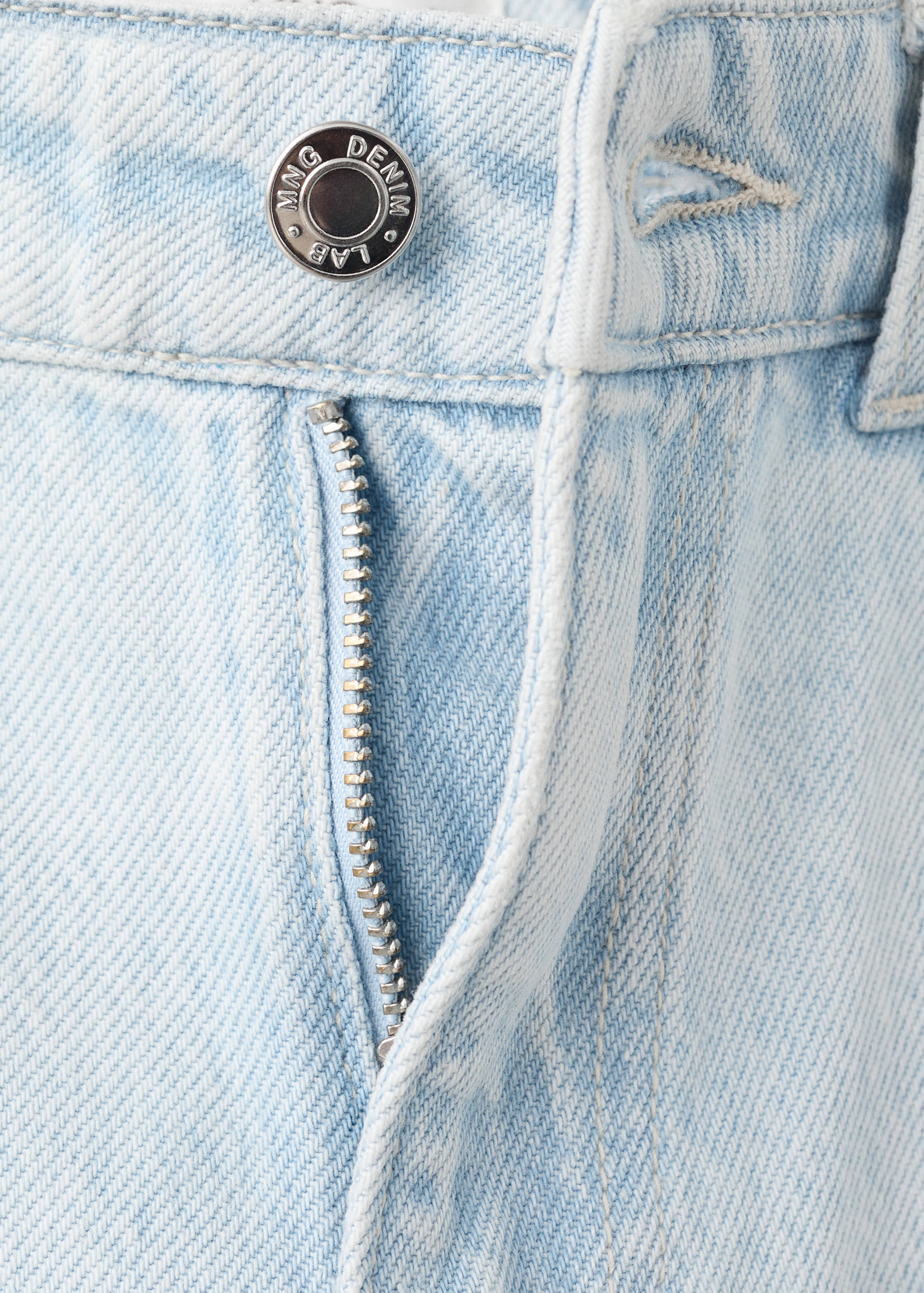 Close-up of light blue denim trousers waistband and zip fly.